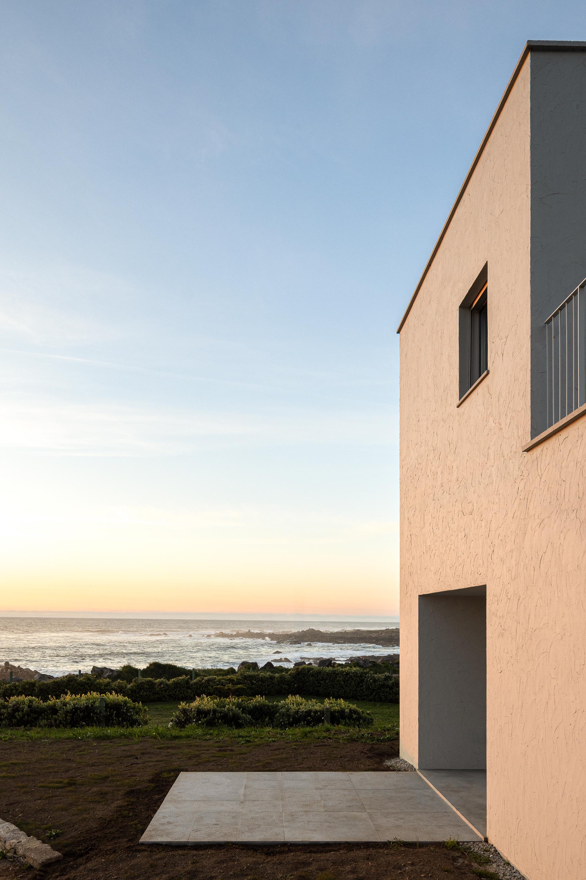 Fachada da moradia branca ao pôr do sol, com terraço exterior e vista para o mar — CASA ÂNCORA arquitectura Tiago Sousa Arquitecto fotografia Ivo Tavares