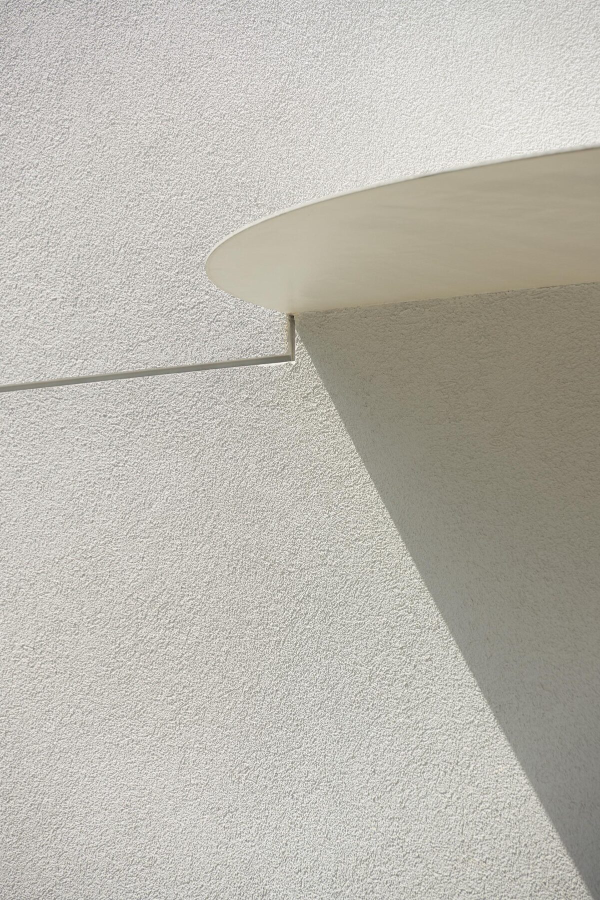 Detalhe da fachada em EPS projetado branco com textura rugosa e elemento curvo superior, sob luz solar — Farmácia São João arquitectura Tsou Arquitectos fotografia Ivo Tavares