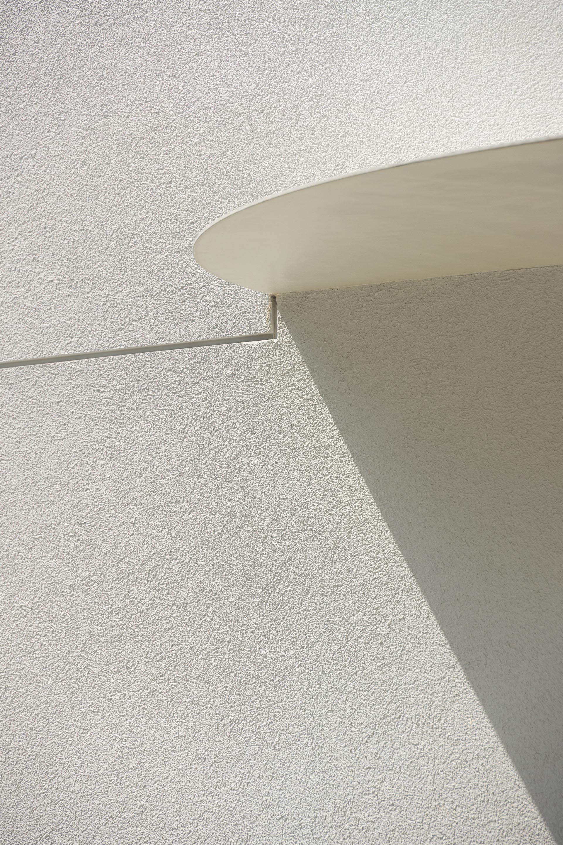 Detalhe da fachada em EPS projetado branco com textura rugosa e elemento curvo superior, sob luz solar — Farmácia São João arquitectura Tsou Arquitectos fotografia Ivo Tavares