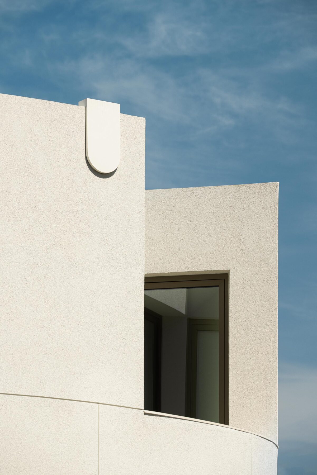 Varanda exterior curva com pavimento cerâmico e paredes brancas, em contacto com a vegetação — Farmácia São João arquitectura Tsou Arquitectos fotografia Ivo Tavares