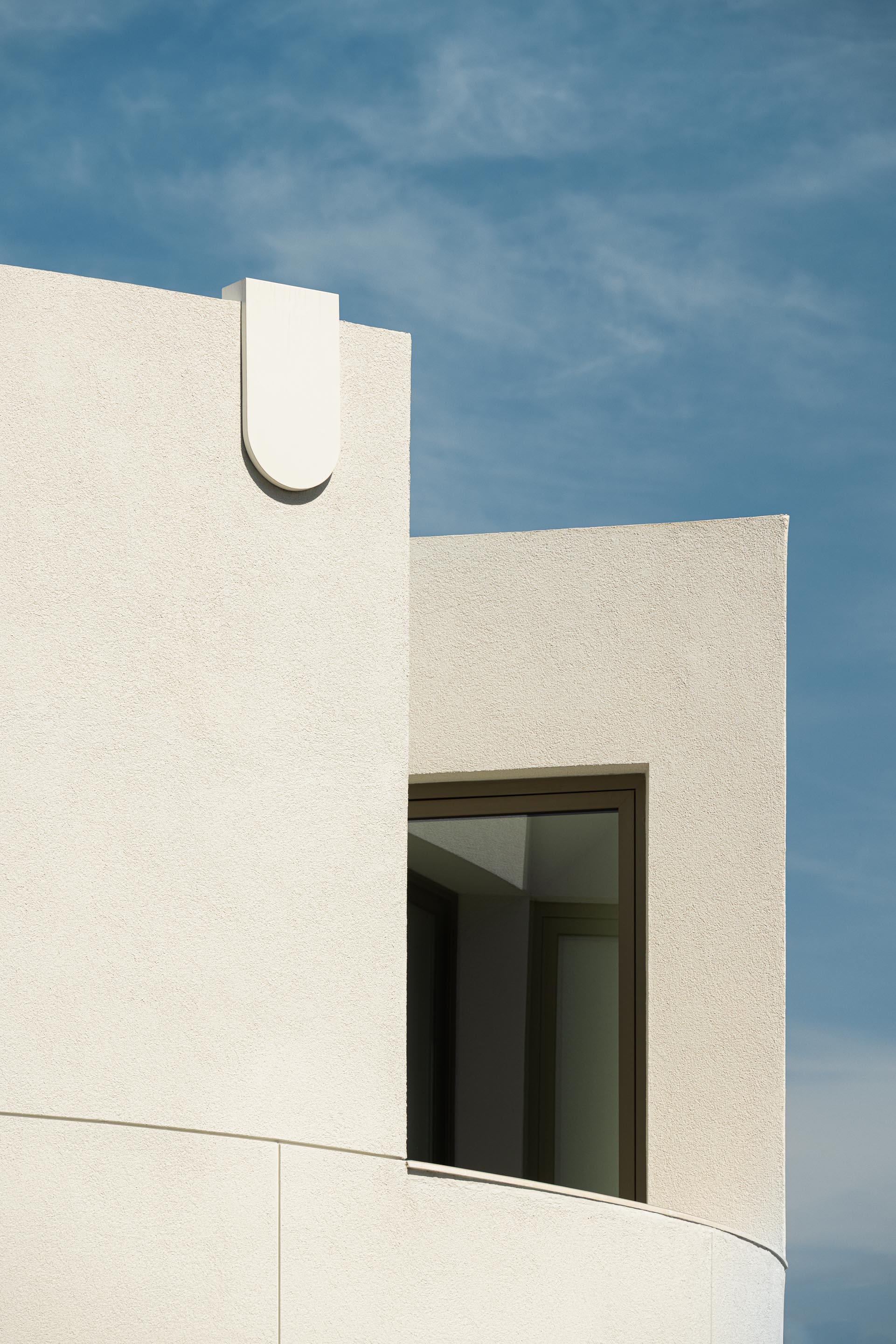 Varanda exterior curva com pavimento cerâmico e paredes brancas, em contacto com a vegetação — Farmácia São João arquitectura Tsou Arquitectos fotografia Ivo Tavares