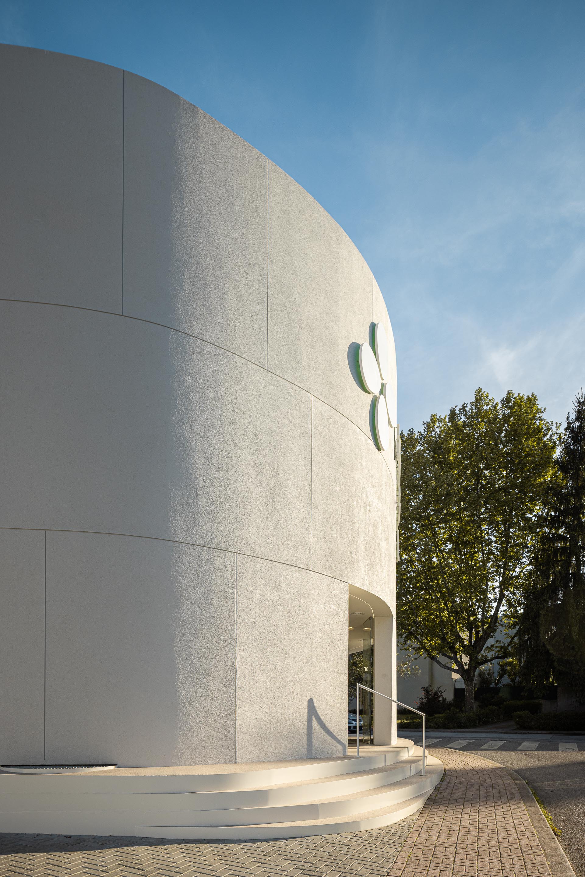 Fachada curva em EPS projetado branco com sinalética em relevo e entrada com degraus curvos — Farmácia São João arquitectura Tsou Arquitectos fotografia Ivo Tavares