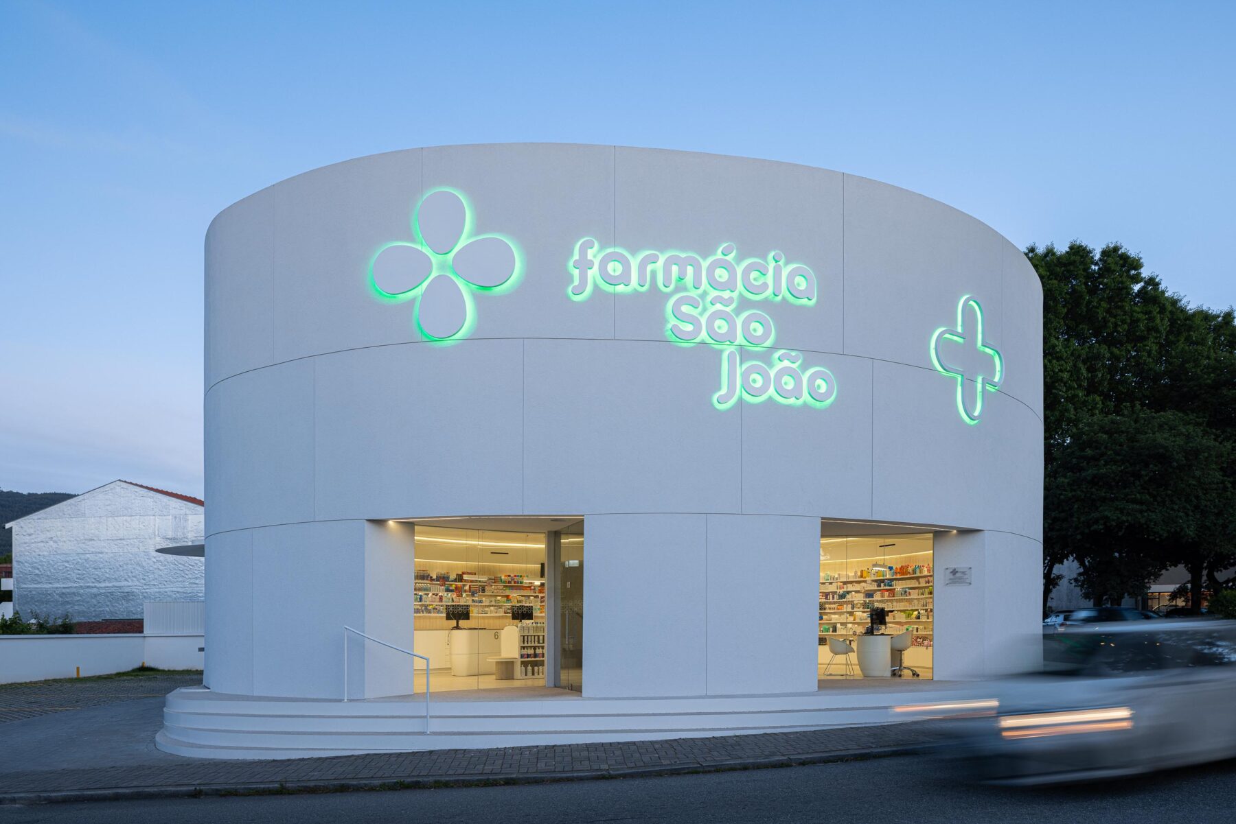 Degraus curvos em mármore de Estremoz jateado e fachada em EPS projetado branco, com porta envidraçada — Farmácia São João arquitectura Tsou Arquitectos fotografia Ivo Tavares