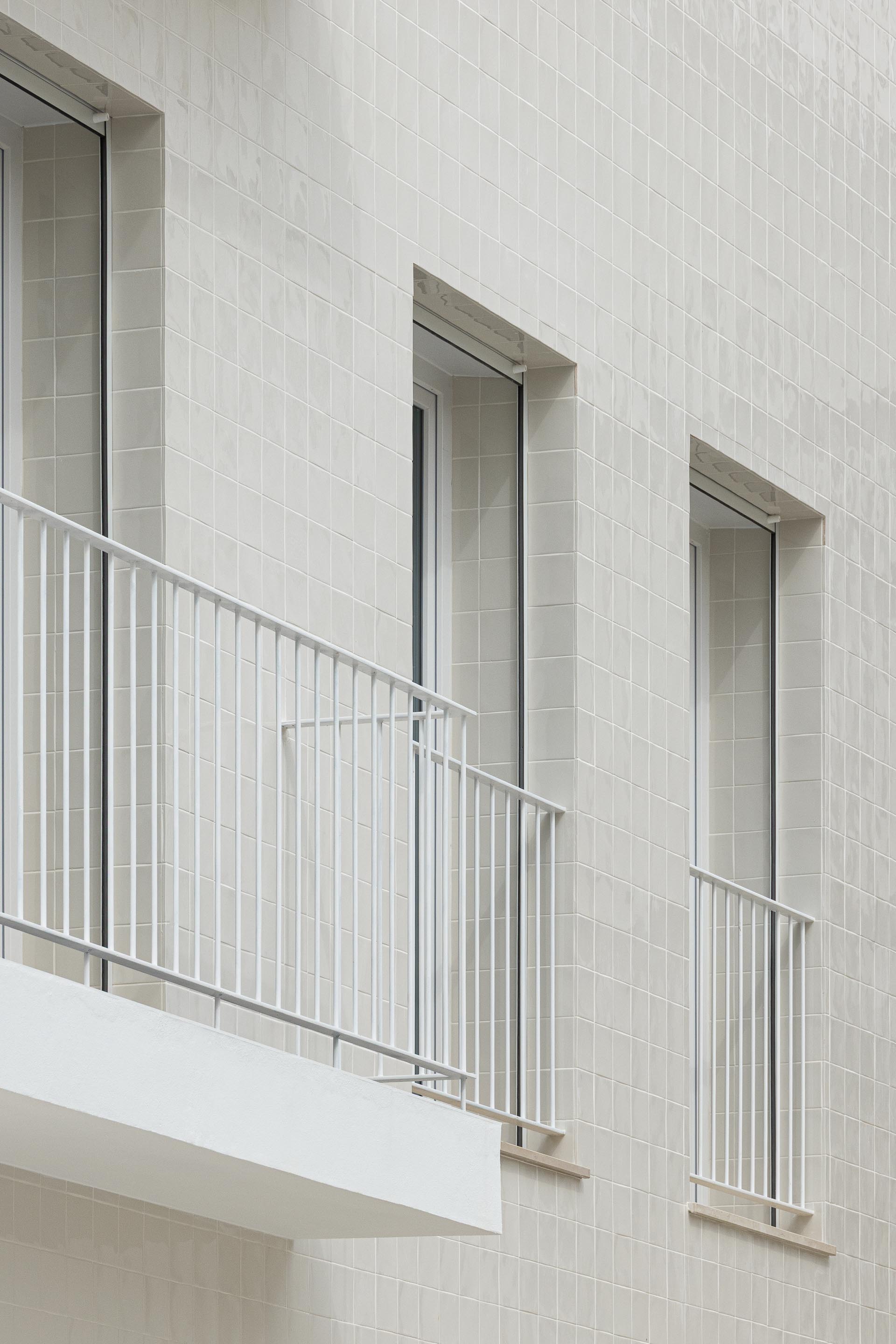 Pormenor da fachada em azulejo branco com textura e guarda-corpos metálicos brancos nos vãos — Edifício Actriz Virginia arquitectura Adarq – André David Arquitecto fotografia Ivo Tavares