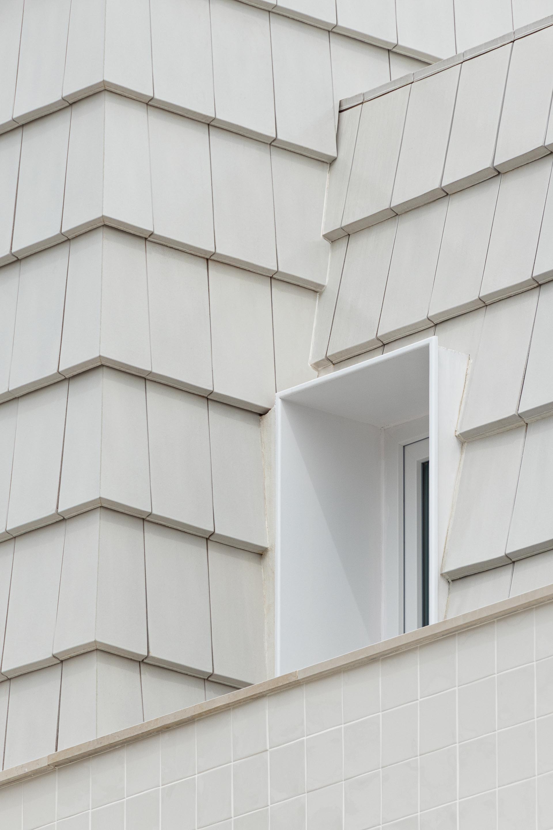Detalhe da transição entre a fachada em azulejo branco e a cobertura amansardada em telha plana branca. Vão recuado — Edifício Actriz Virginia arquitectura Adarq – André David Arquitecto fotografia Ivo Tavares
