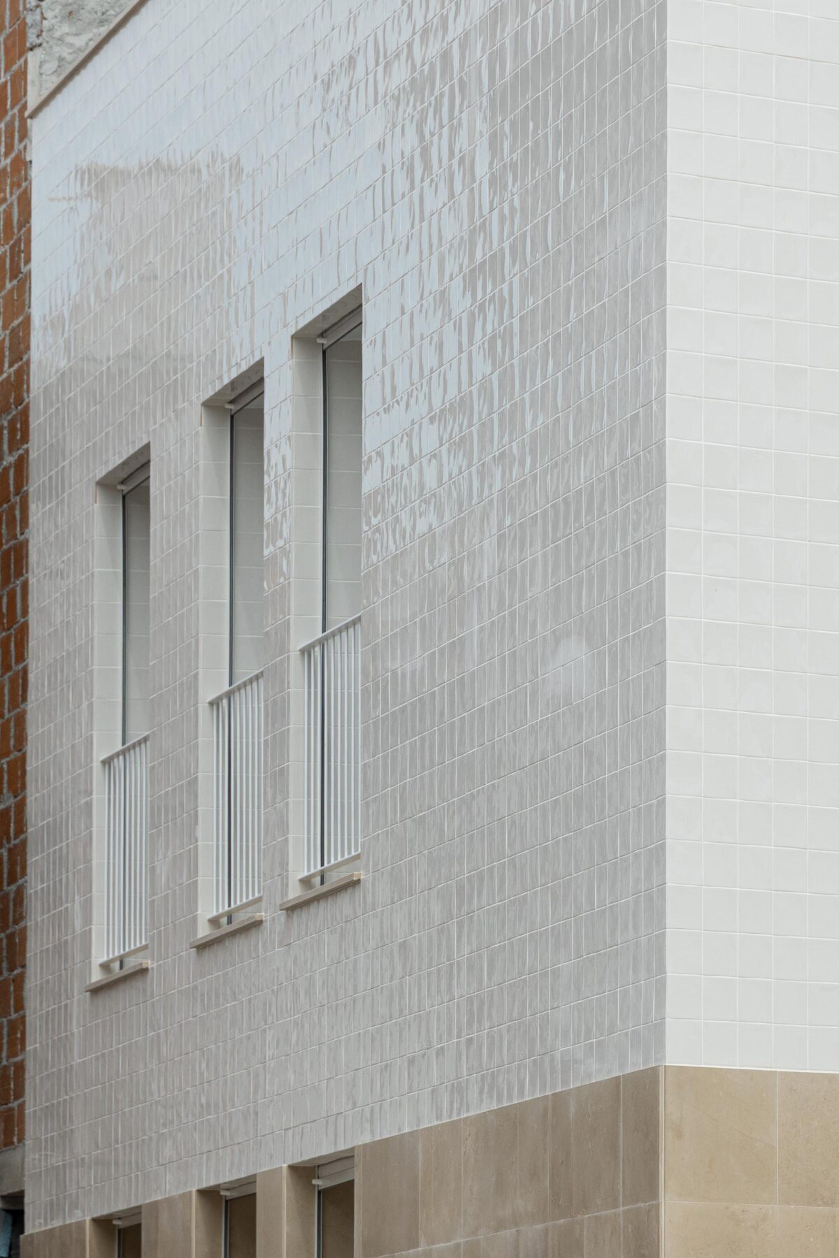 Pormenor da fachada em azulejo branco com reflexos e textura. Vãos verticais com caixilharia branca e guarda-corpos — Edifício Actriz Virginia arquitectura Adarq – André David Arquitecto fotografia Ivo Tavares