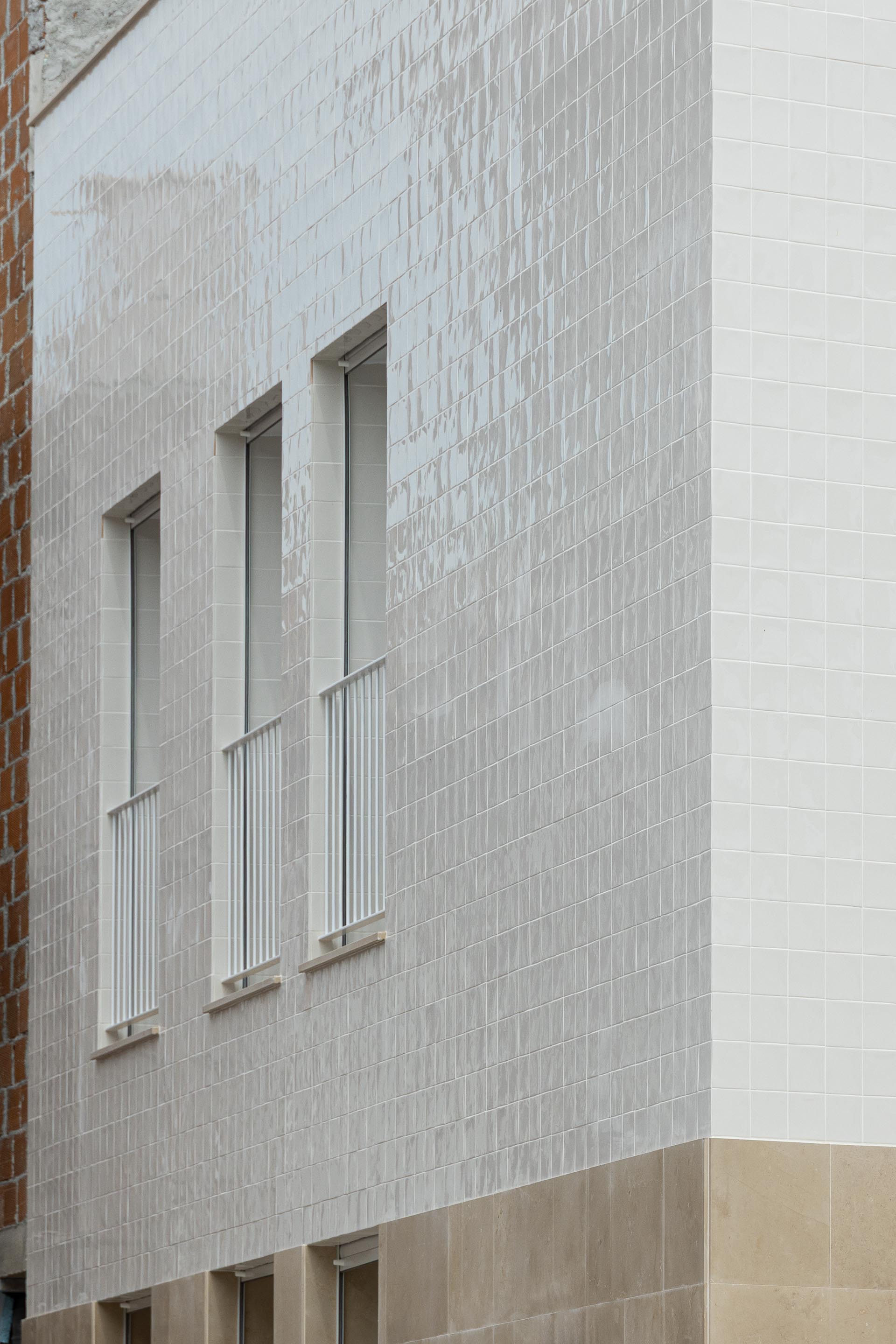 Pormenor da fachada em azulejo branco com reflexos e textura. Vãos verticais com caixilharia branca e guarda-corpos — Edifício Actriz Virginia arquitectura Adarq – André David Arquitecto fotografia Ivo Tavares
