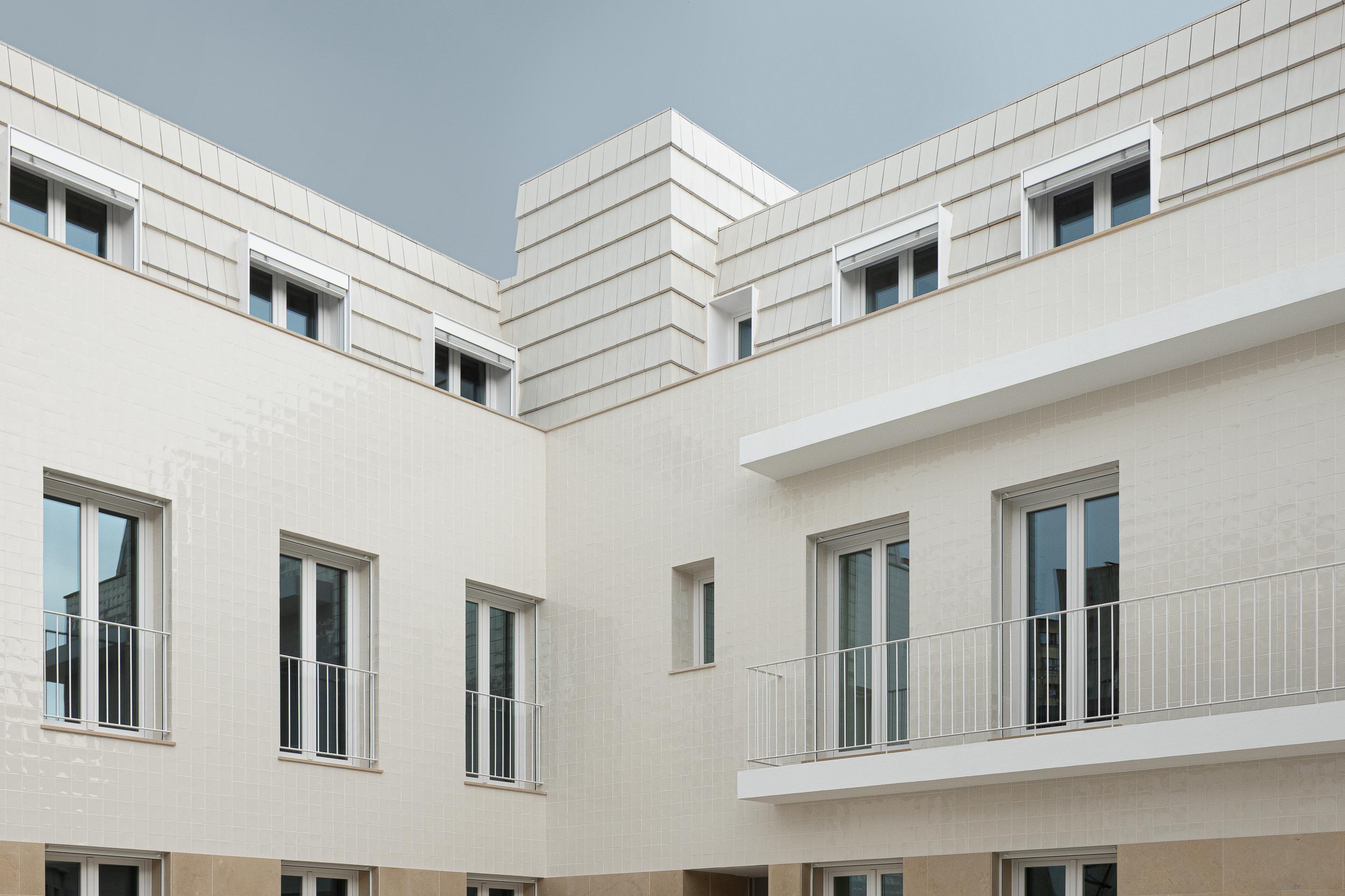 Pormenor da esquina do edifício, com fachada em azulejo branco e cobertura amansardada em telha plana. Vãos recuados — Edifício Actriz Virginia arquitectura Adarq – André David Arquitecto fotografia Ivo Tavares