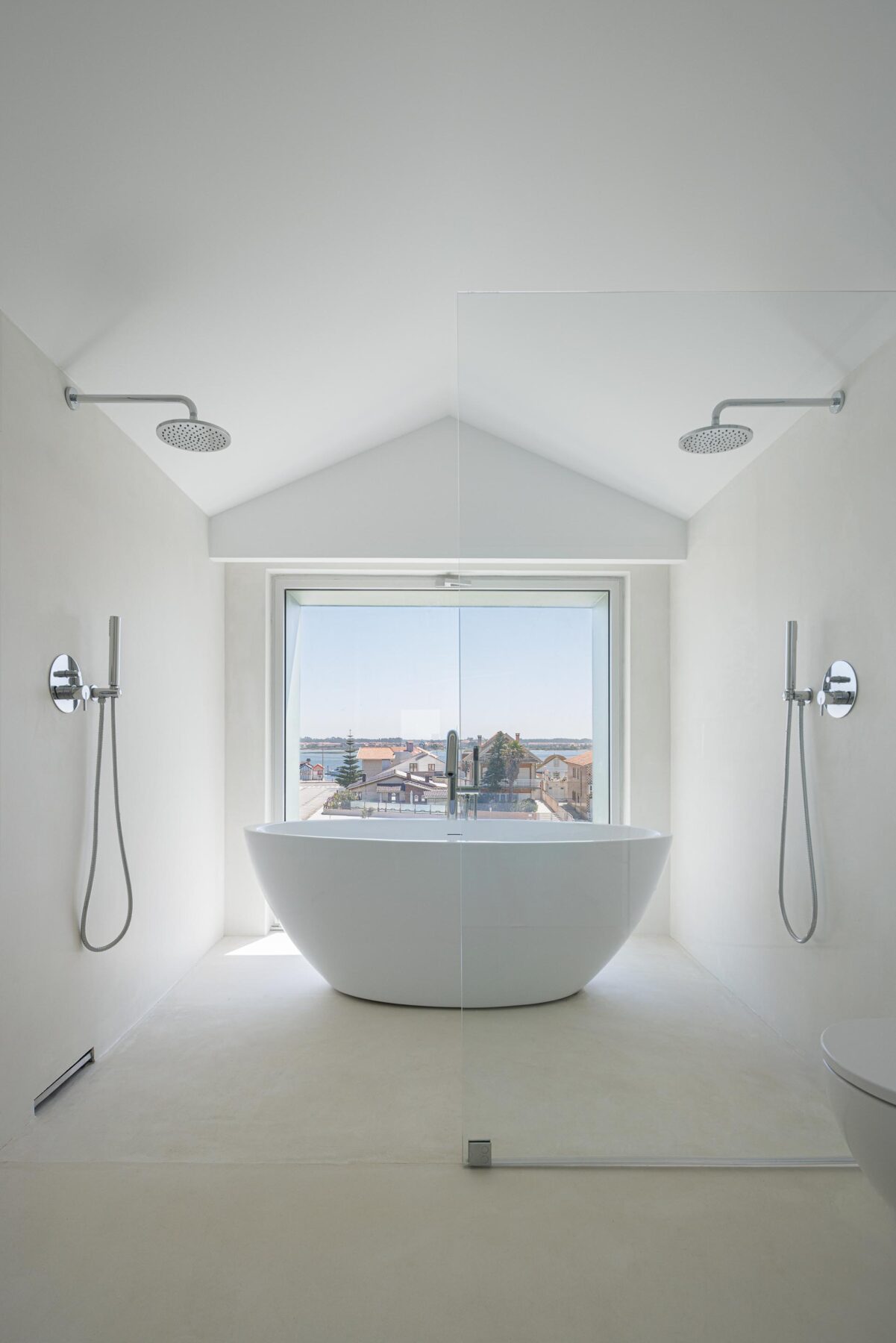 Interior da casa de banho com banheira freestanding, pavimento branco e grande vão envidraçado com vista para a paisagem — Casa Verde arquitectura M2 Senos Arquitectos fotografia Ivo Tavares
