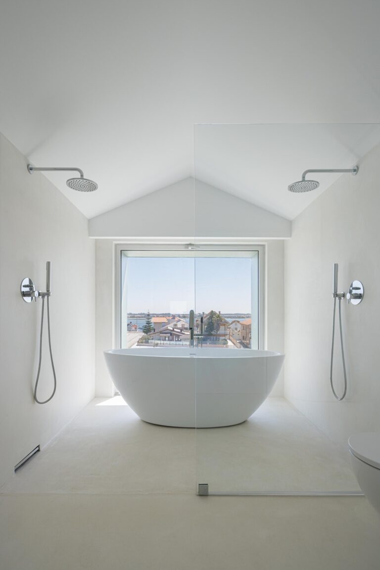 Interior da casa de banho com banheira freestanding, pavimento branco e grande vão envidraçado com vista para a paisagem — Casa Verde arquitectura M2 Senos Arquitectos fotografia Ivo Tavares