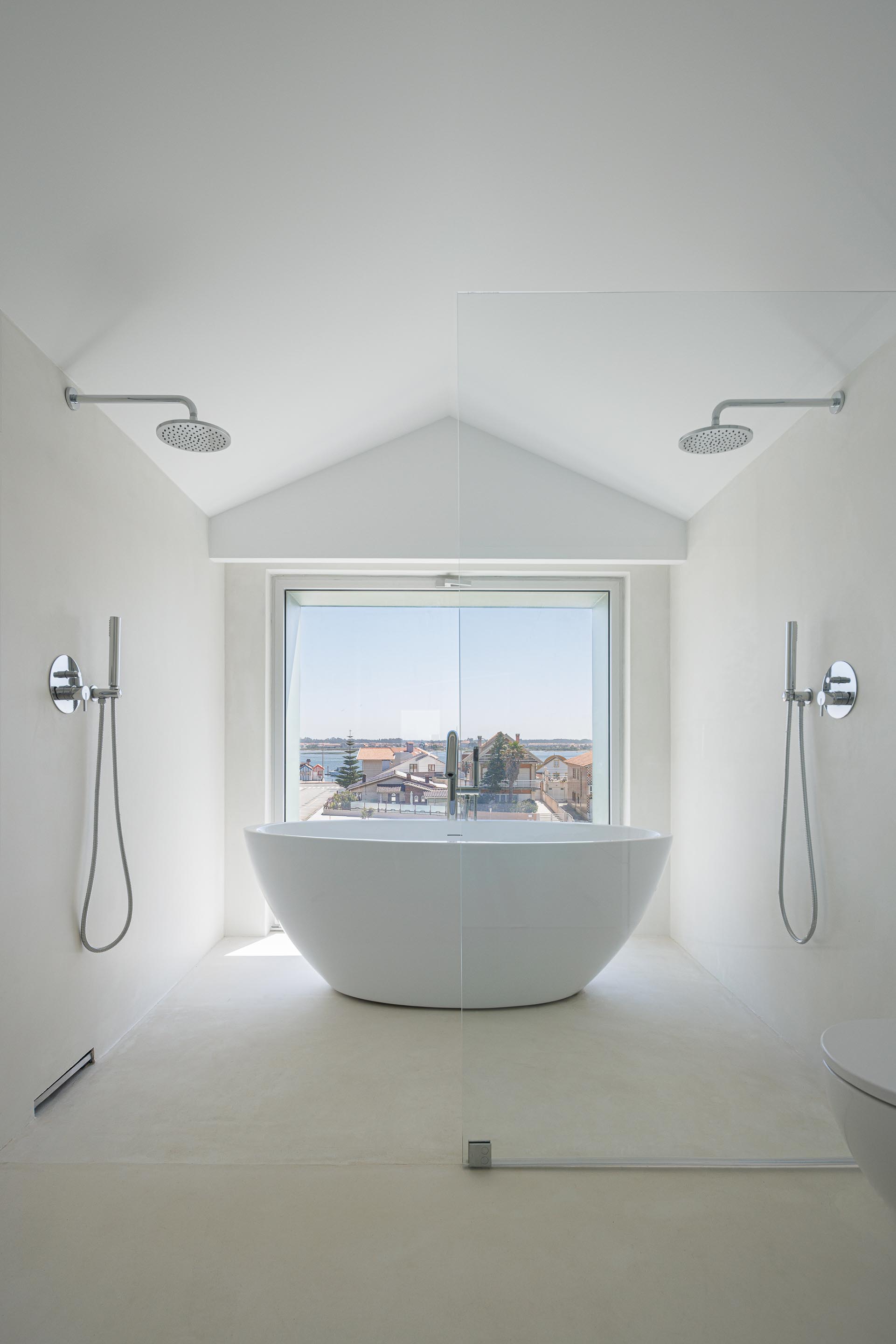 Interior da casa de banho com banheira freestanding, pavimento branco e grande vão envidraçado com vista para a paisagem — Casa Verde arquitectura M2 Senos Arquitectos fotografia Ivo Tavares