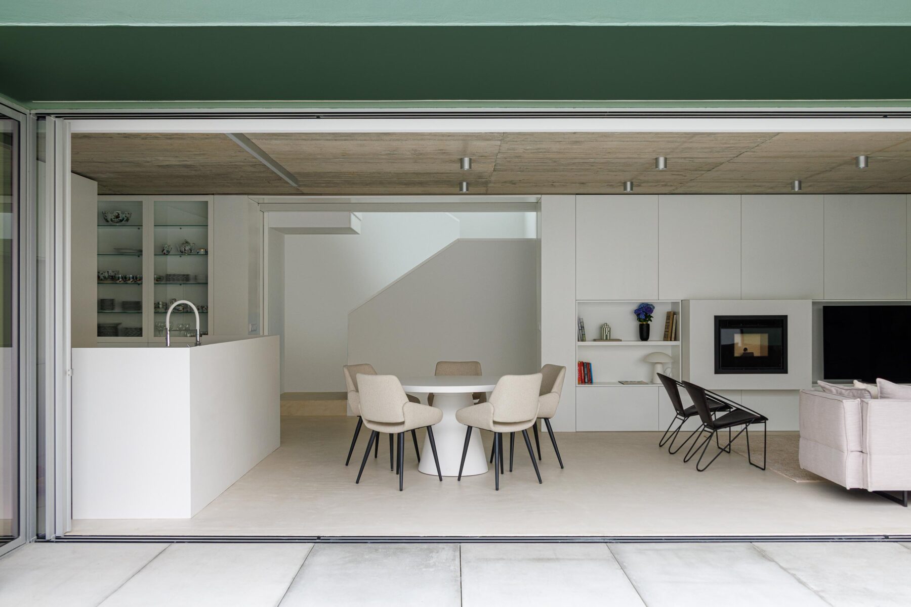 Interior da sala de estar e jantar com tecto em betão aparente e continuidade visual para o logradouro através de vãos amplos — Casa Verde arquitectura M2 Senos Arquitectos fotografia Ivo Tavares