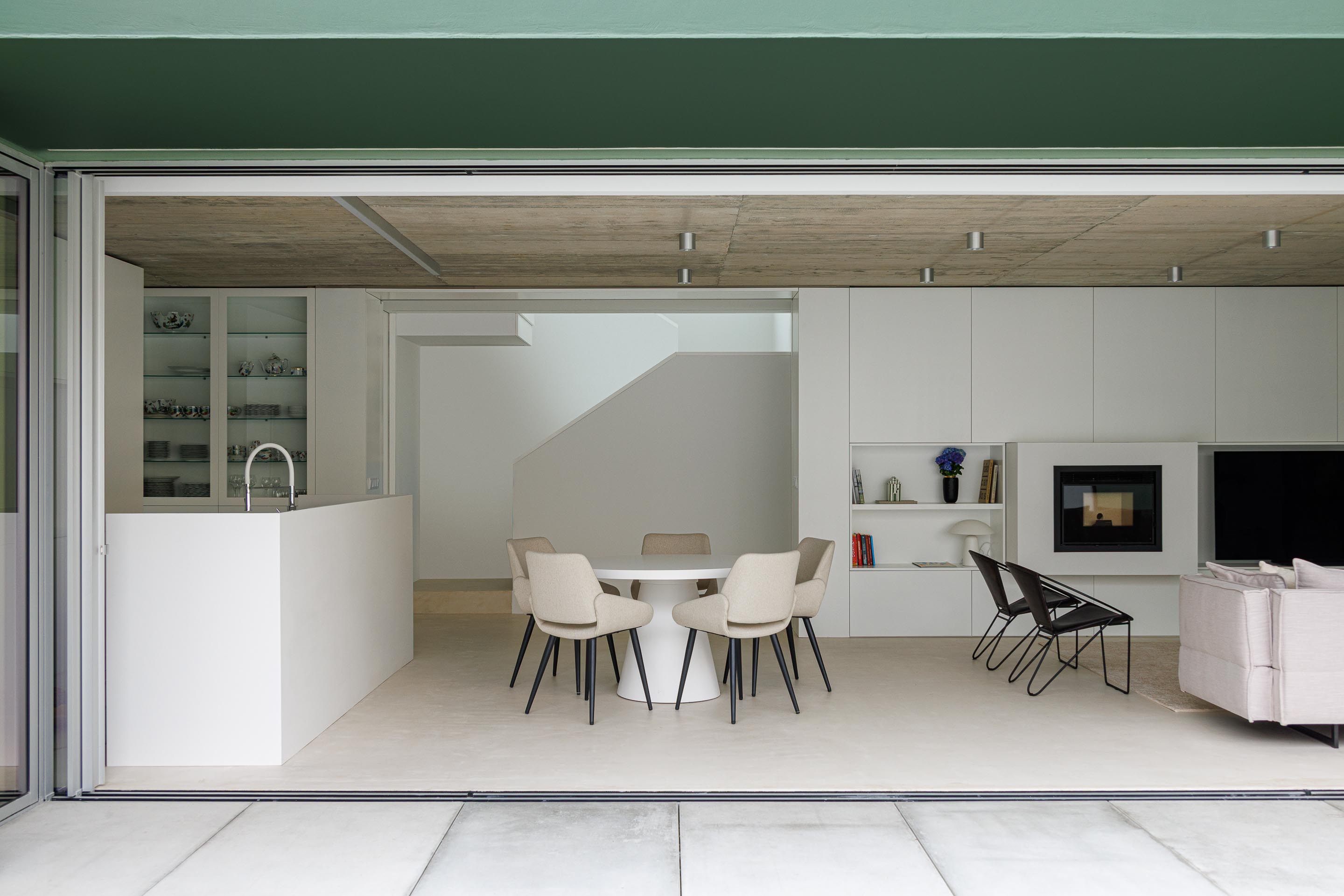 Interior da sala de estar e jantar com tecto em betão aparente e continuidade visual para o logradouro através de vãos amplos — Casa Verde arquitectura M2 Senos Arquitectos fotografia Ivo Tavares