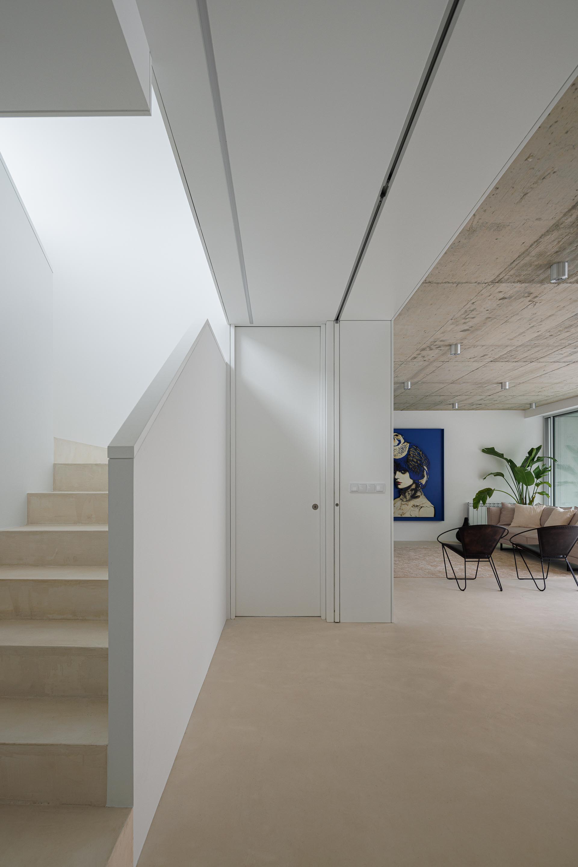Hall de entrada com escada de pavimento claro e paredes brancas, contrastando com o tecto em betão aparente — Casa Verde arquitectura M2 Senos Arquitectos fotografia Ivo Tavares