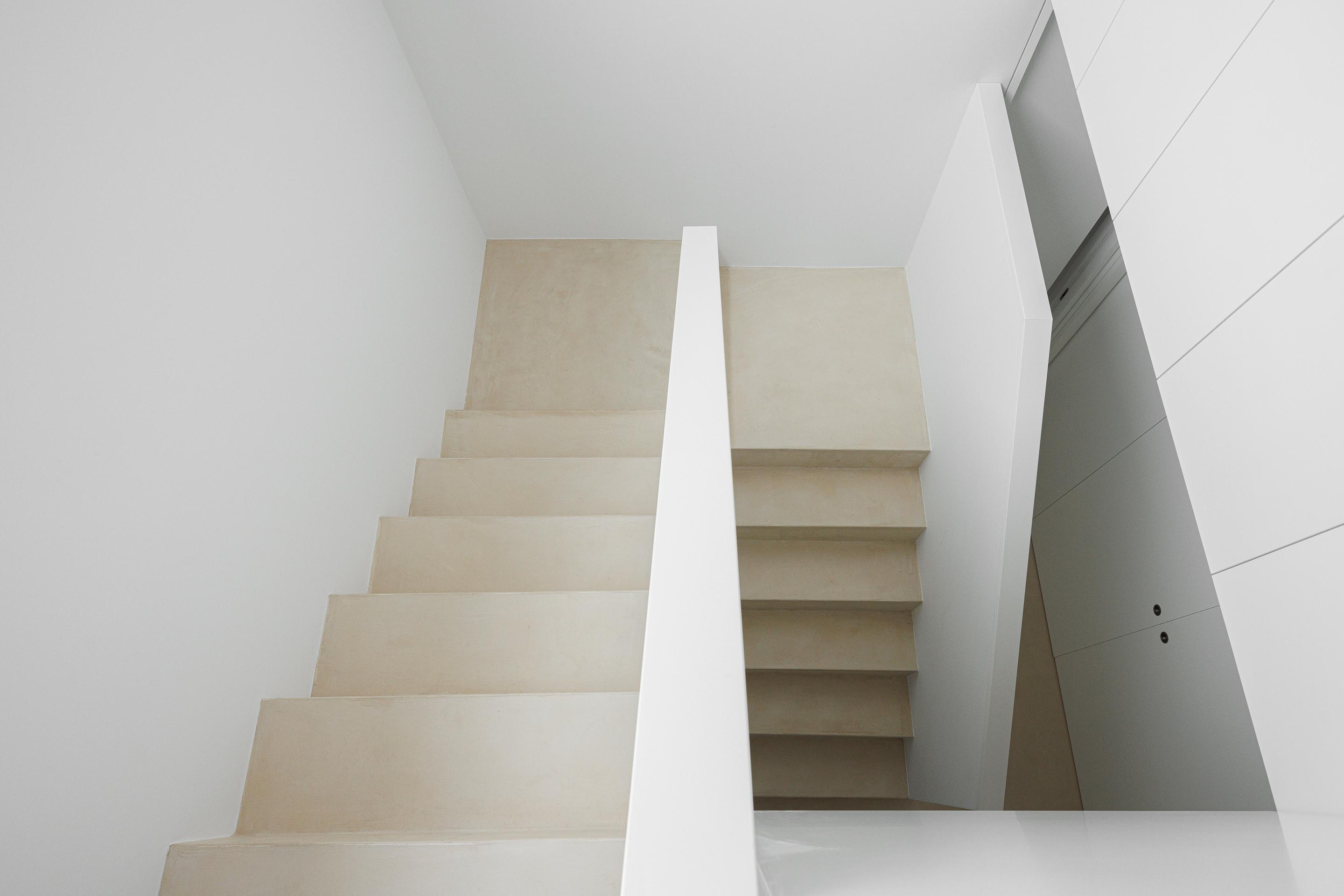 Escada interior com degraus de pavimento claro e guardacorpos brancos, destacando a geometria simples do espaço — Casa Verde arquitectura M2 Senos Arquitectos fotografia Ivo Tavares