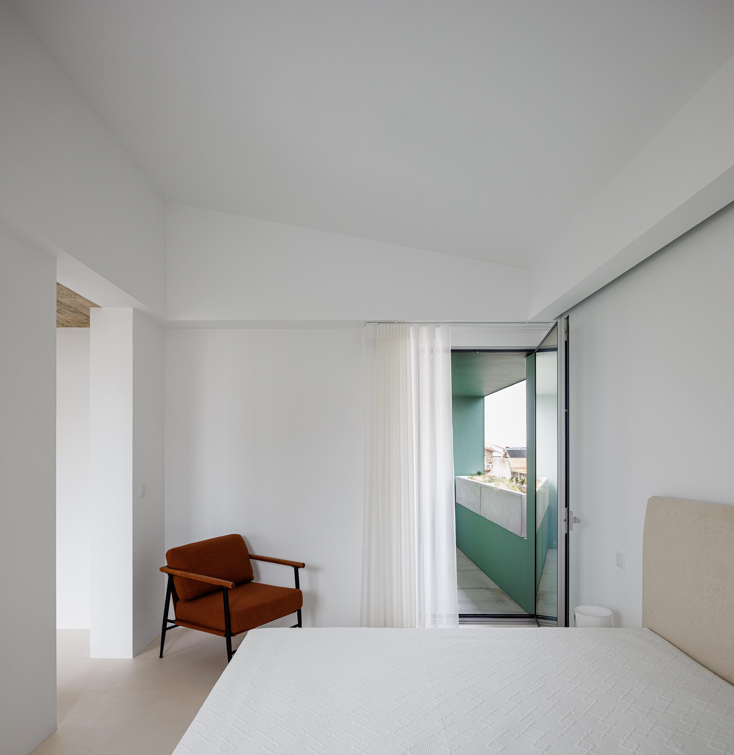 Interior do quarto com paredes brancas, pavimento claro e acesso a uma varanda exterior com vegetação — Casa Verde arquitectura M2 Senos Arquitectos fotografia Ivo Tavares