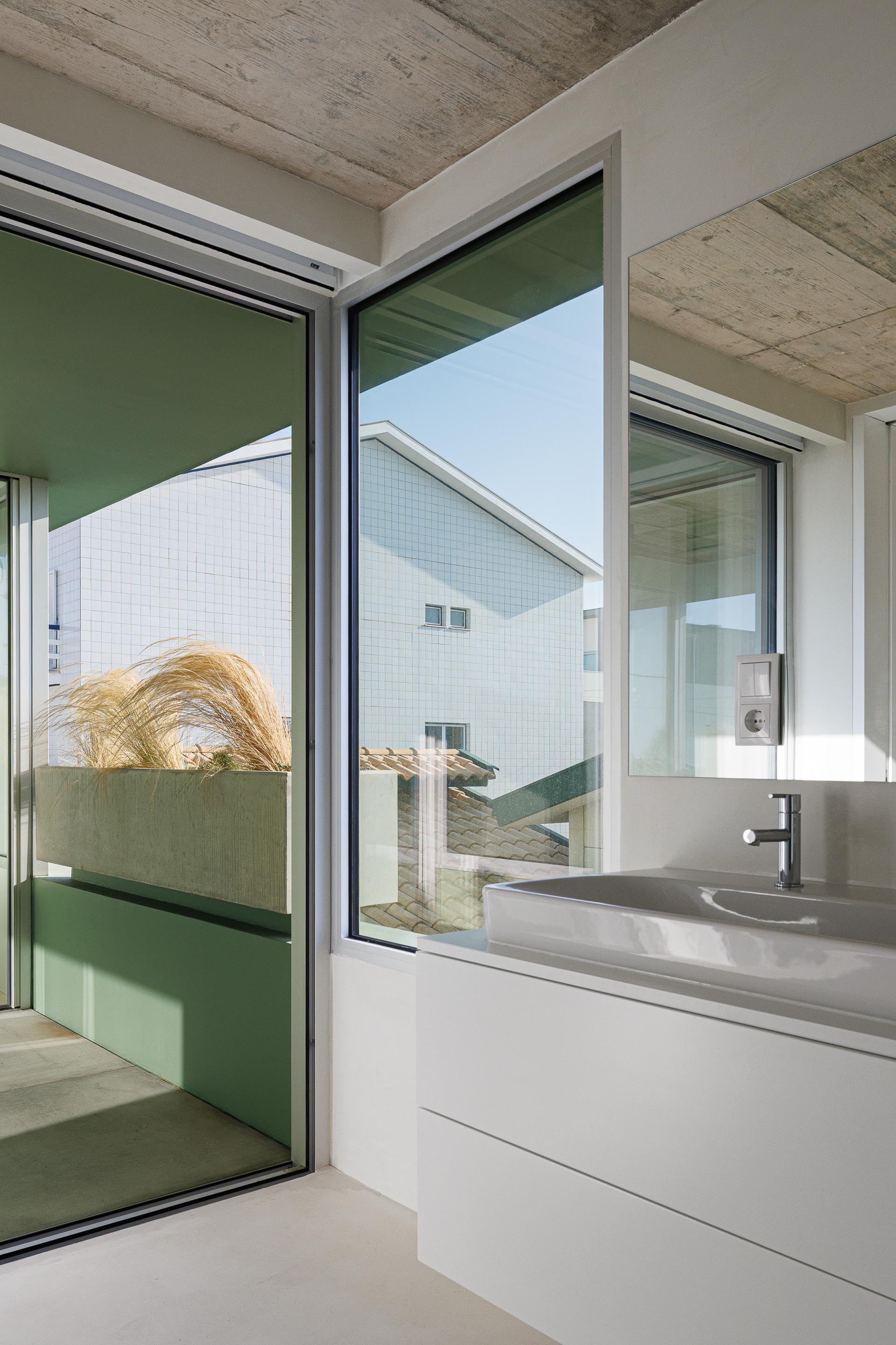 Interior da casa de banho com lavatório branco, tecto em betão aparente e vista para o exterior através de vão — Casa Verde arquitectura M2 Senos Arquitectos fotografia Ivo Tavares