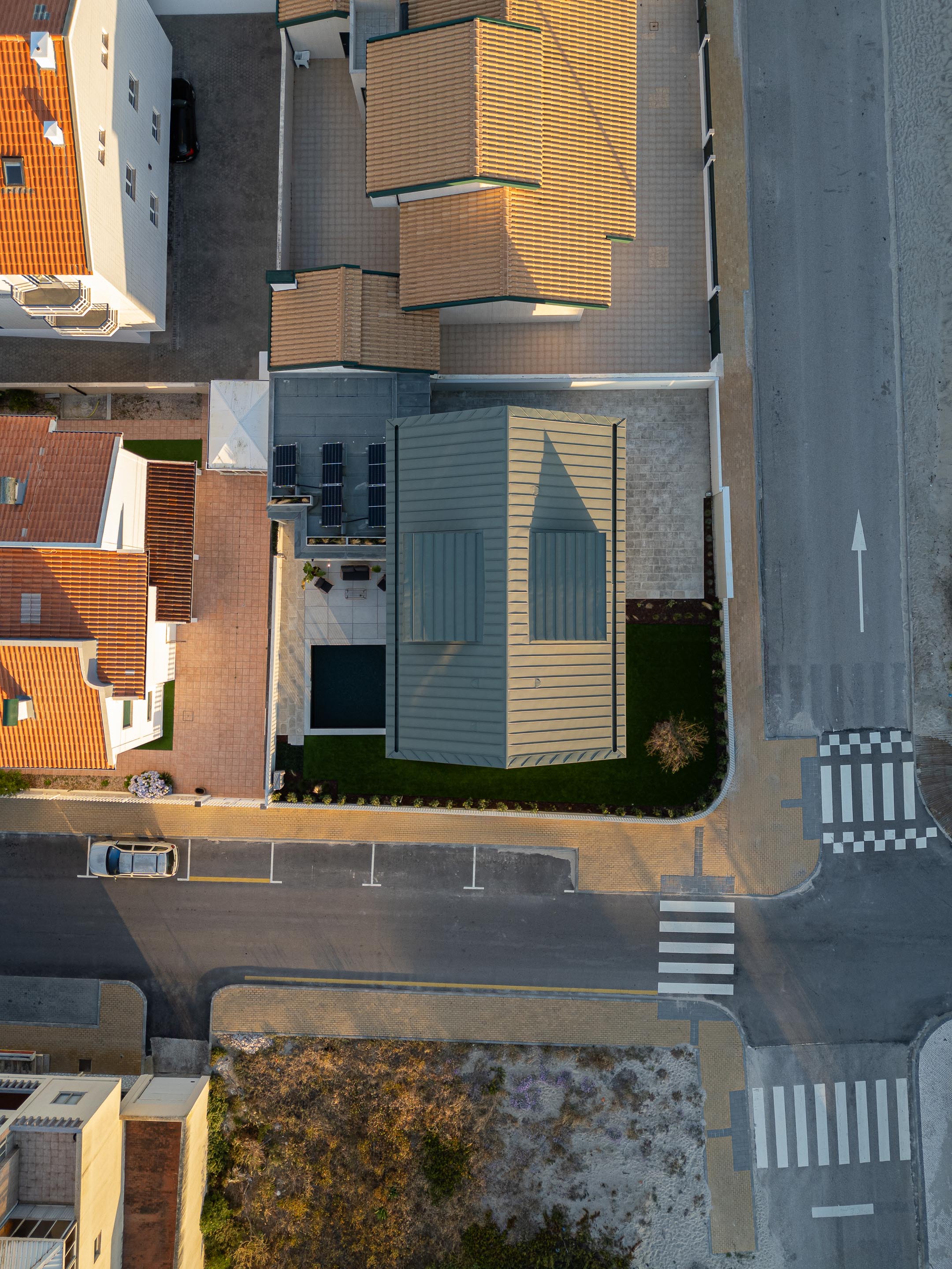 Vista aérea da moradia com cobertura inclinada em zinco verde, piscina quadrada e painéis solares no terraço — Casa Verde arquitectura M2 Senos Arquitectos fotografia Ivo Tavares