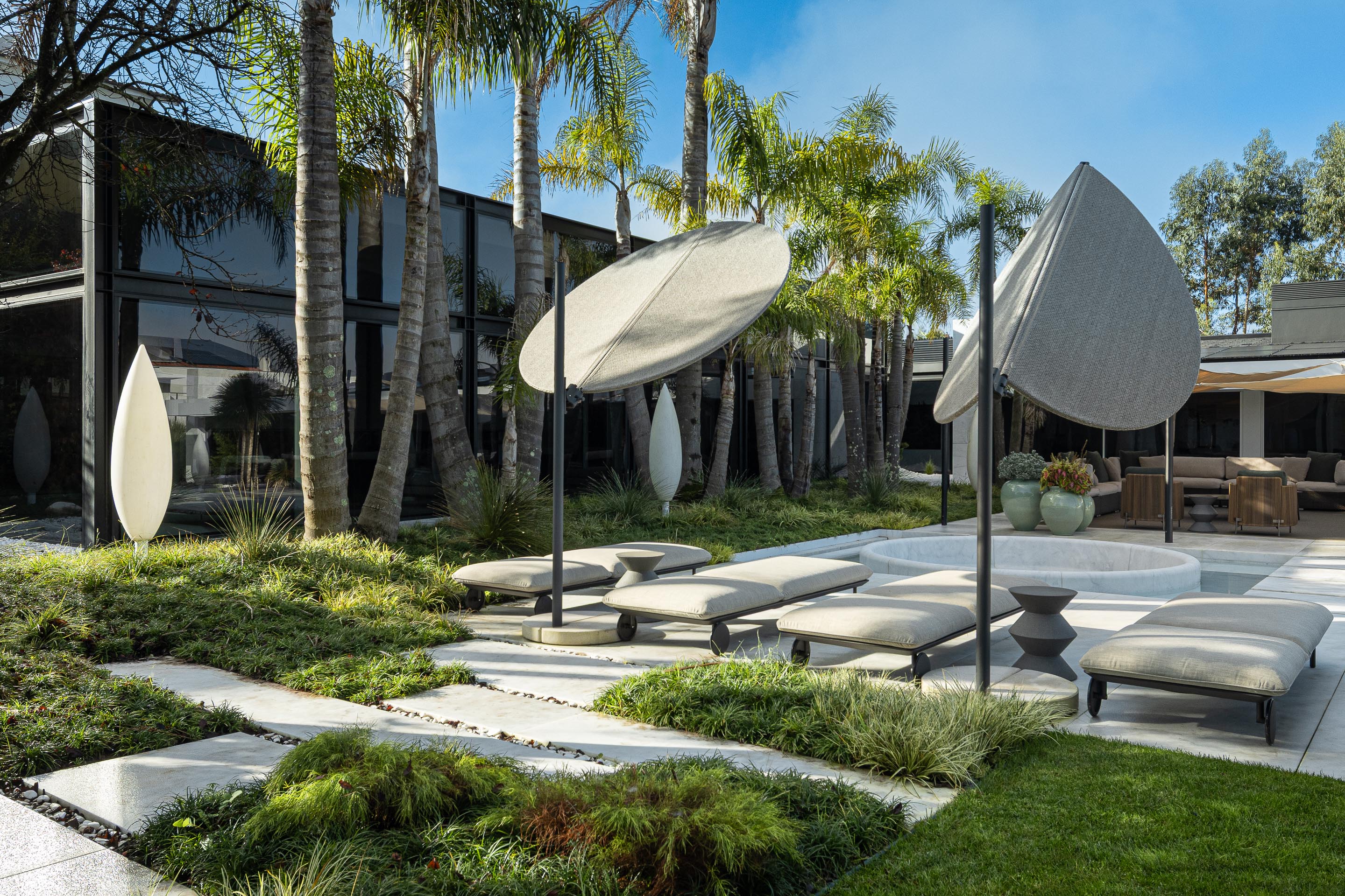 Zona da piscina com espreguiçadeiras e candeeiros de exterior, integrada num jardim com vegetação densa e seixos brancos — RiscoWhite arquitectura Risco Singular – Arquitectura, Lda. fotografia Ivo Tavares