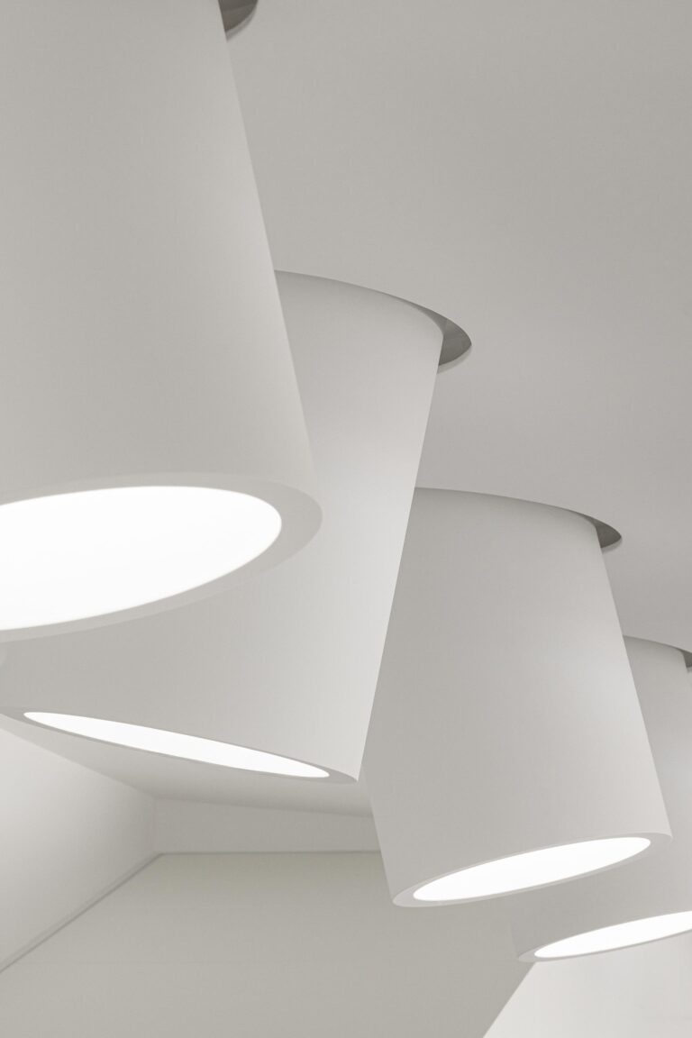Detalhe de candeeiros cilíndricos brancos suspensos do teto, criando iluminação pontual e design minimalista — RiscoWhite arquitectura Risco Singular – Arquitectura, Lda. fotografia Ivo Tavares