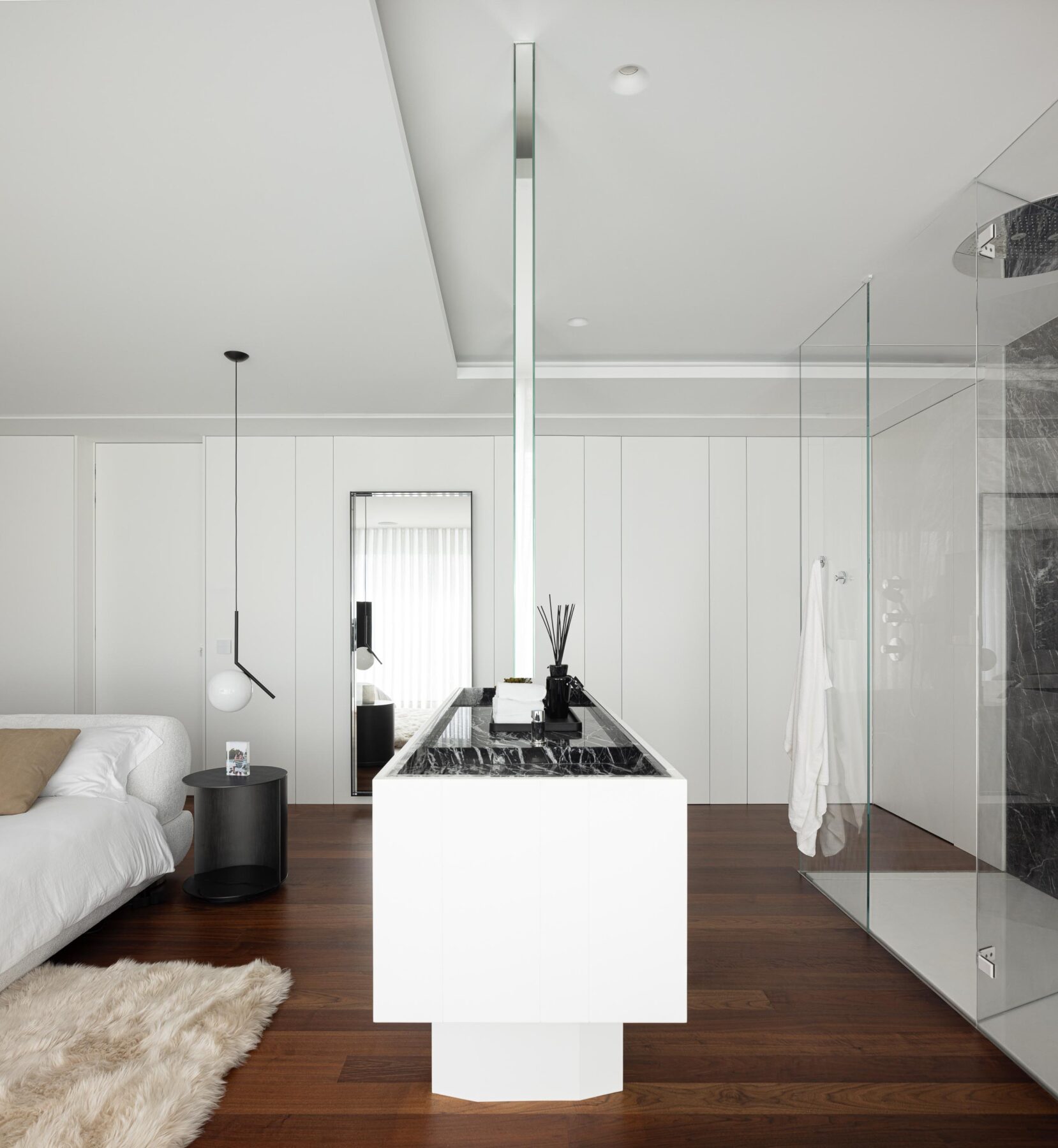 Detalhe da casa de banho integrada no quarto, com lavatório branco, parede em mármore negro e divisória de vidro — RiscoWhite arquitectura Risco Singular – Arquitectura, Lda. fotografia Ivo Tavares