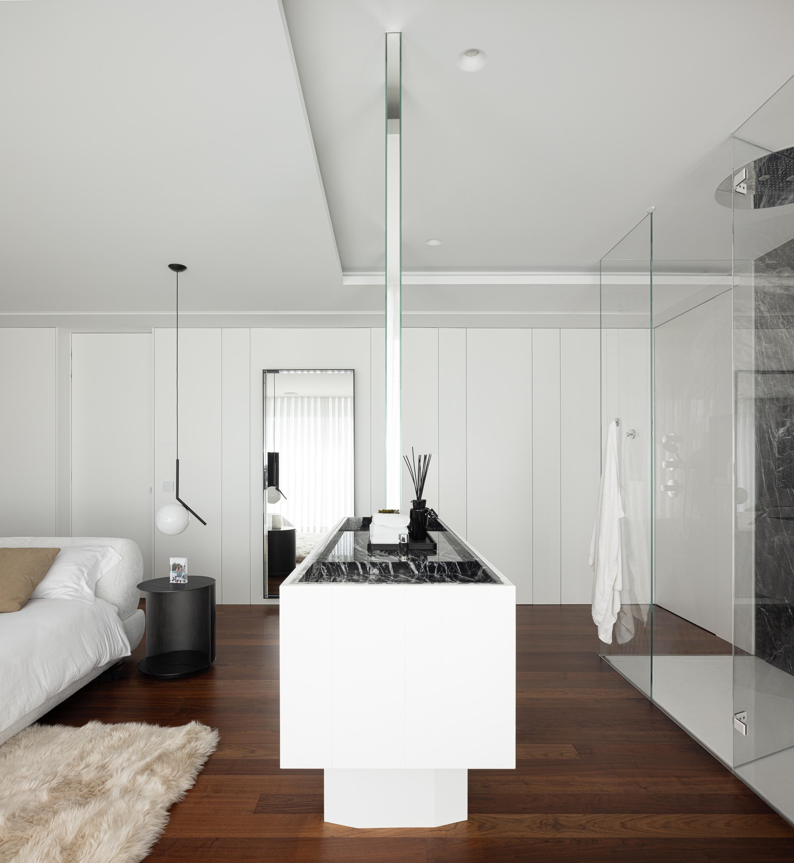 Detalhe da casa de banho integrada no quarto, com lavatório branco, parede em mármore negro e divisória de vidro — RiscoWhite arquitectura Risco Singular – Arquitectura, Lda. fotografia Ivo Tavares