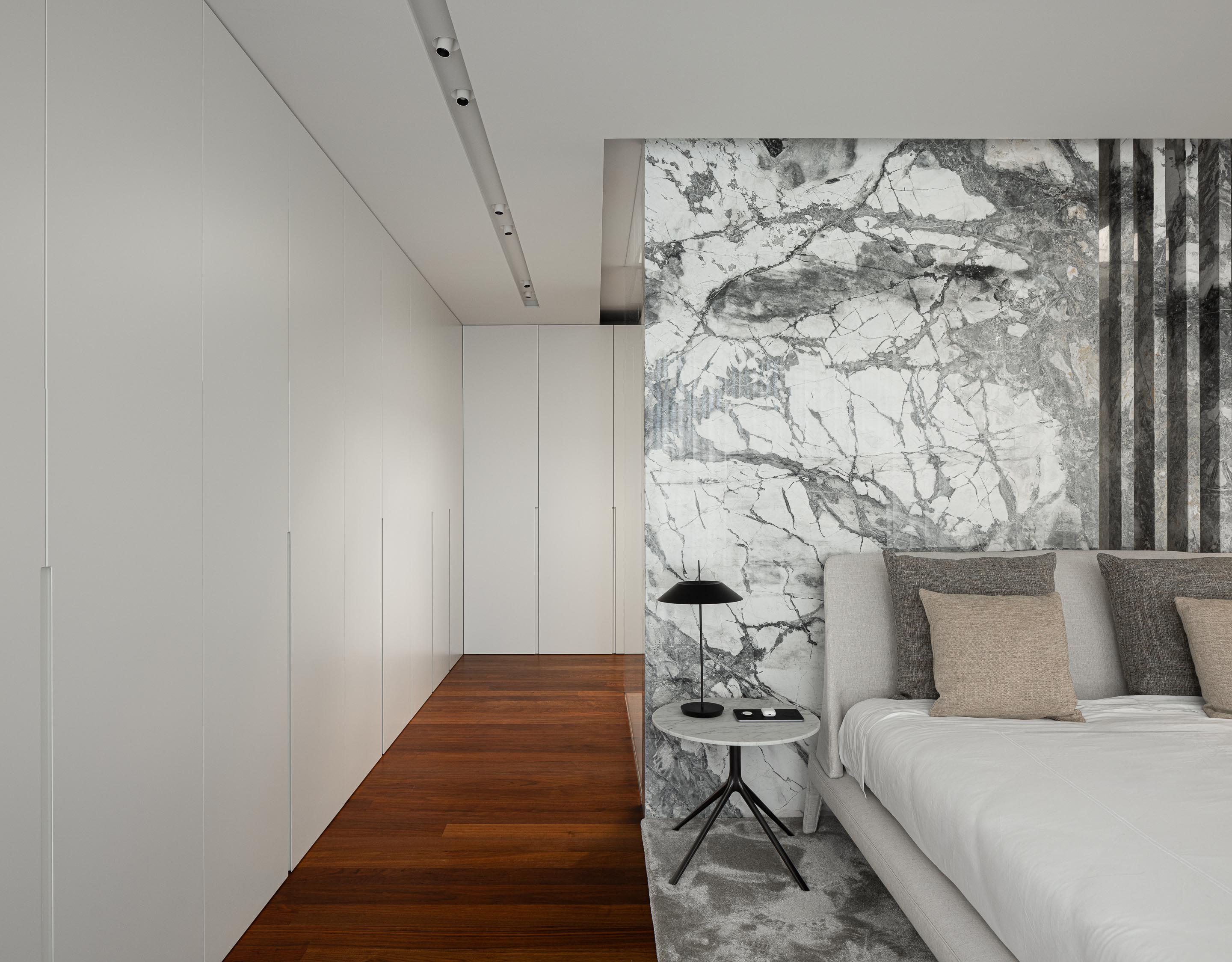Quarto com pavimento em madeira, parede de armários brancos e cabeceira em painel de mármore cinzento — RiscoWhite arquitectura Risco Singular – Arquitectura, Lda. fotografia Ivo Tavares
