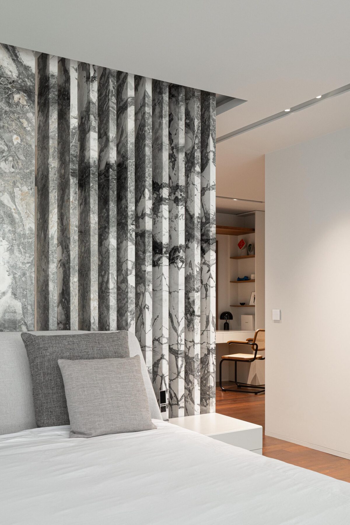Detalhe da cabeceira do quarto com painel de mármore cinzento e ripado vertical, criando textura e profundidade — RiscoWhite arquitectura Risco Singular – Arquitectura, Lda. fotografia Ivo Tavares