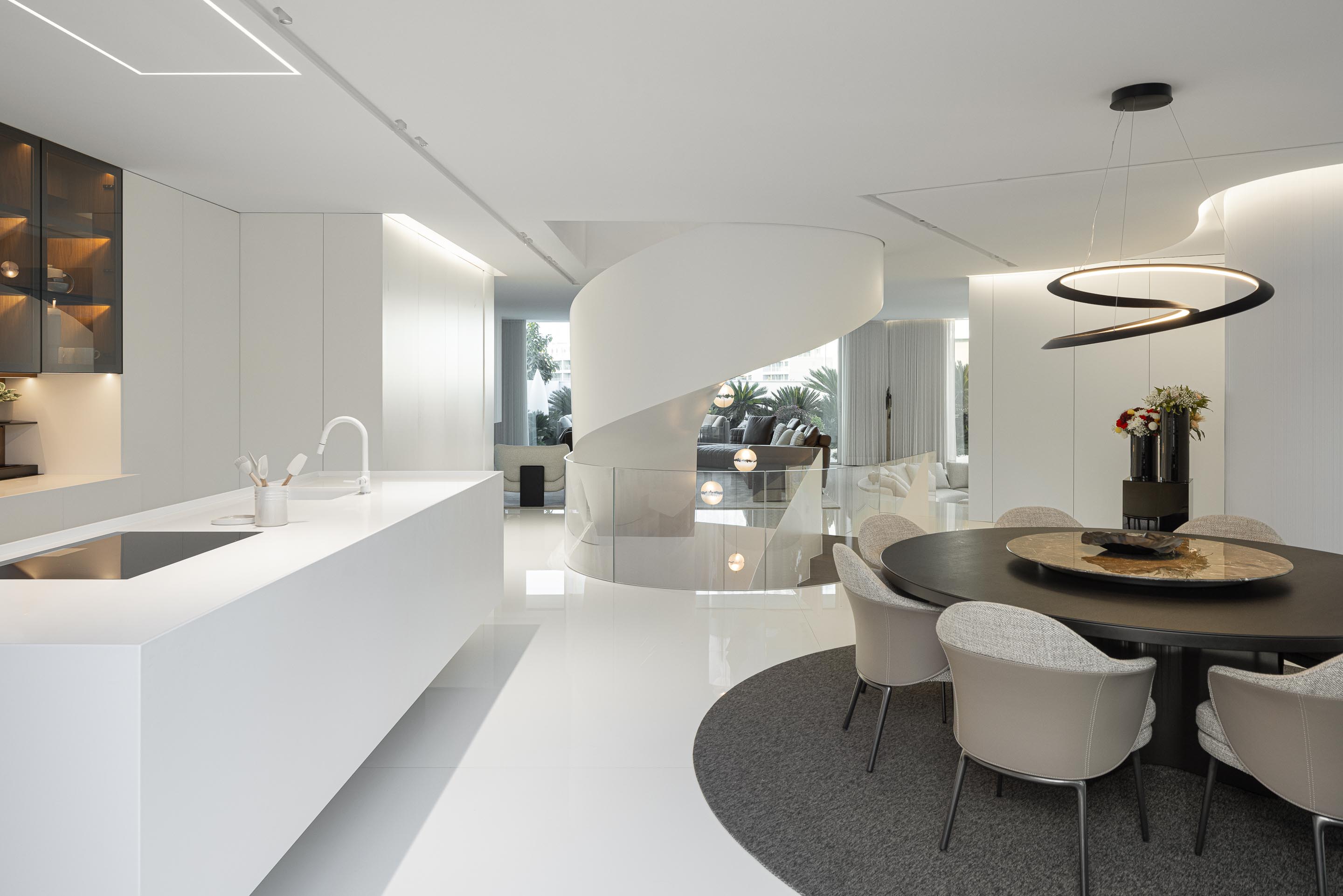 Espaço aberto de cozinha, sala de jantar e estar, com pavimento branco polido e escada em caracol como elemento central — RiscoWhite arquitectura Risco Singular – Arquitectura, Lda. fotografia Ivo Tavares