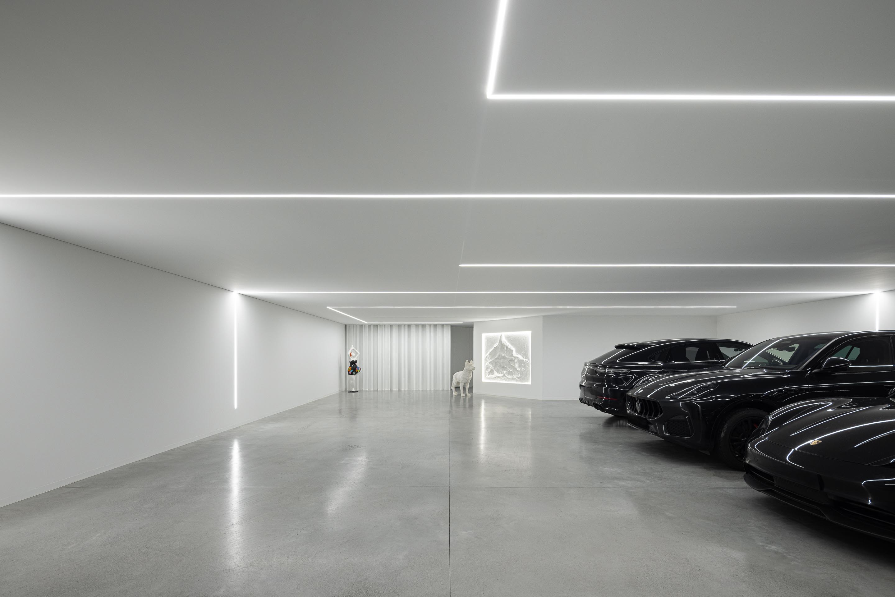 Garagem minimalista com pavimento em betão cinzento, paredes brancas e iluminação linear no teto — RiscoWhite arquitectura Risco Singular – Arquitectura, Lda. fotografia Ivo Tavares