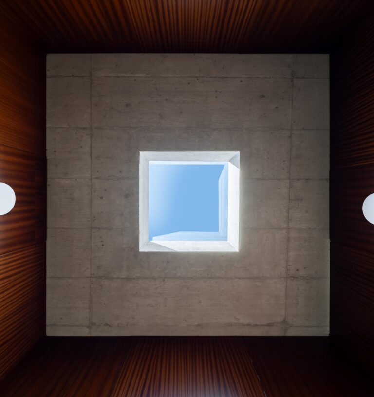 Vista vertical da claraboia quadrada no teto de betão aparente, revelando o céu azul — CASA COQUEIRA arquitectura Tiago Sousa Arquitecto fotografia Ivo Tavares