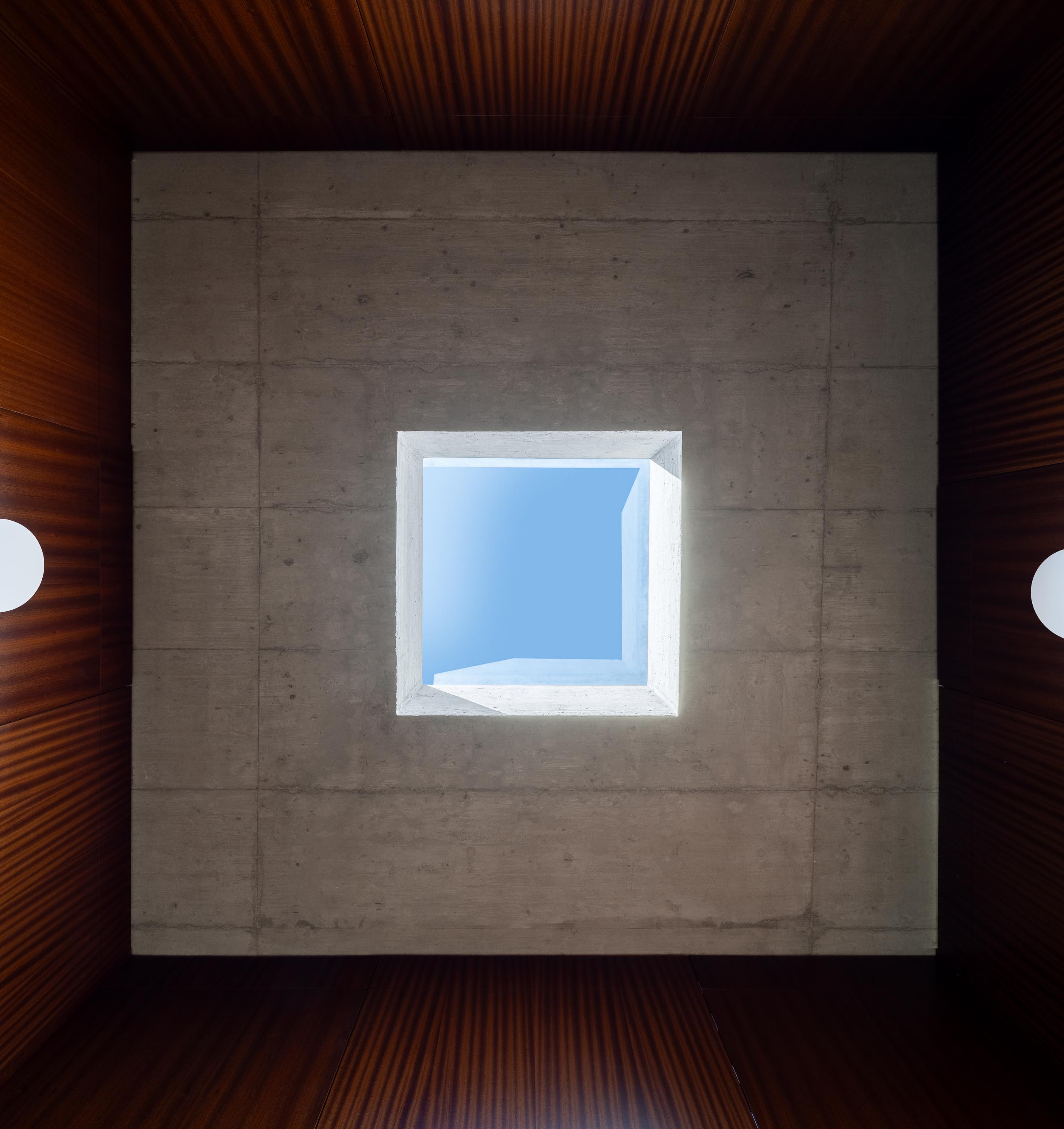 Vista vertical da claraboia quadrada no teto de betão aparente, revelando o céu azul — CASA COQUEIRA arquitectura Tiago Sousa Arquitecto fotografia Ivo Tavares