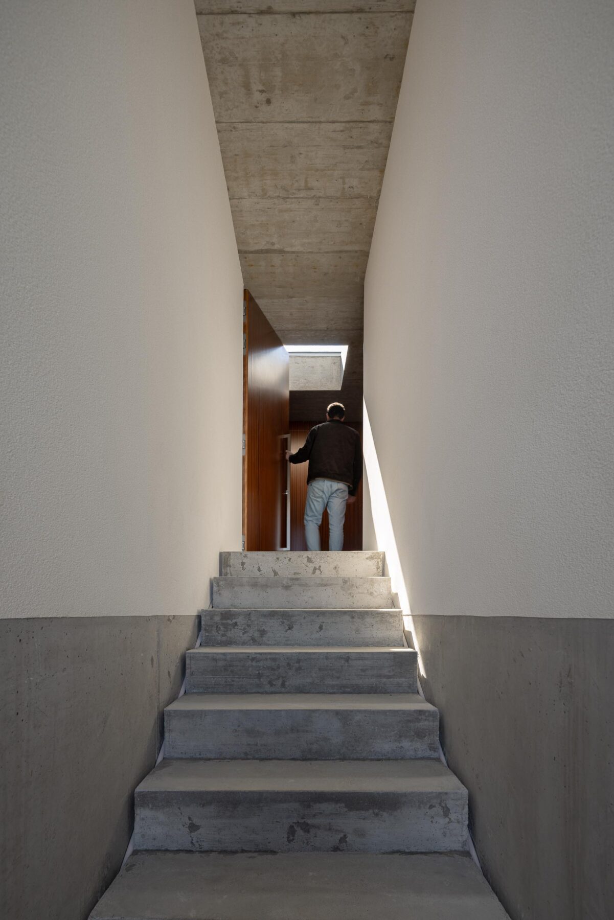 Escadaria de acesso à moradia em betão aparente, ladeada por paredes brancas e teto em betão, com luz zenital — CASA COQUEIRA arquitectura Tiago Sousa Arquitecto fotografia Ivo Tavares