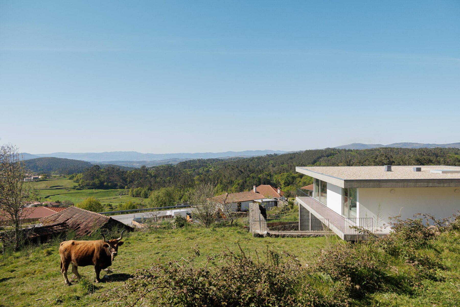 Vista aérea da moradia com cobertura plana em gravilha, varandas e integração na paisagem montanhosa e rural — CASA COQUEIRA arquitectura Tiago Sousa Arquitecto fotografia Ivo Tavares