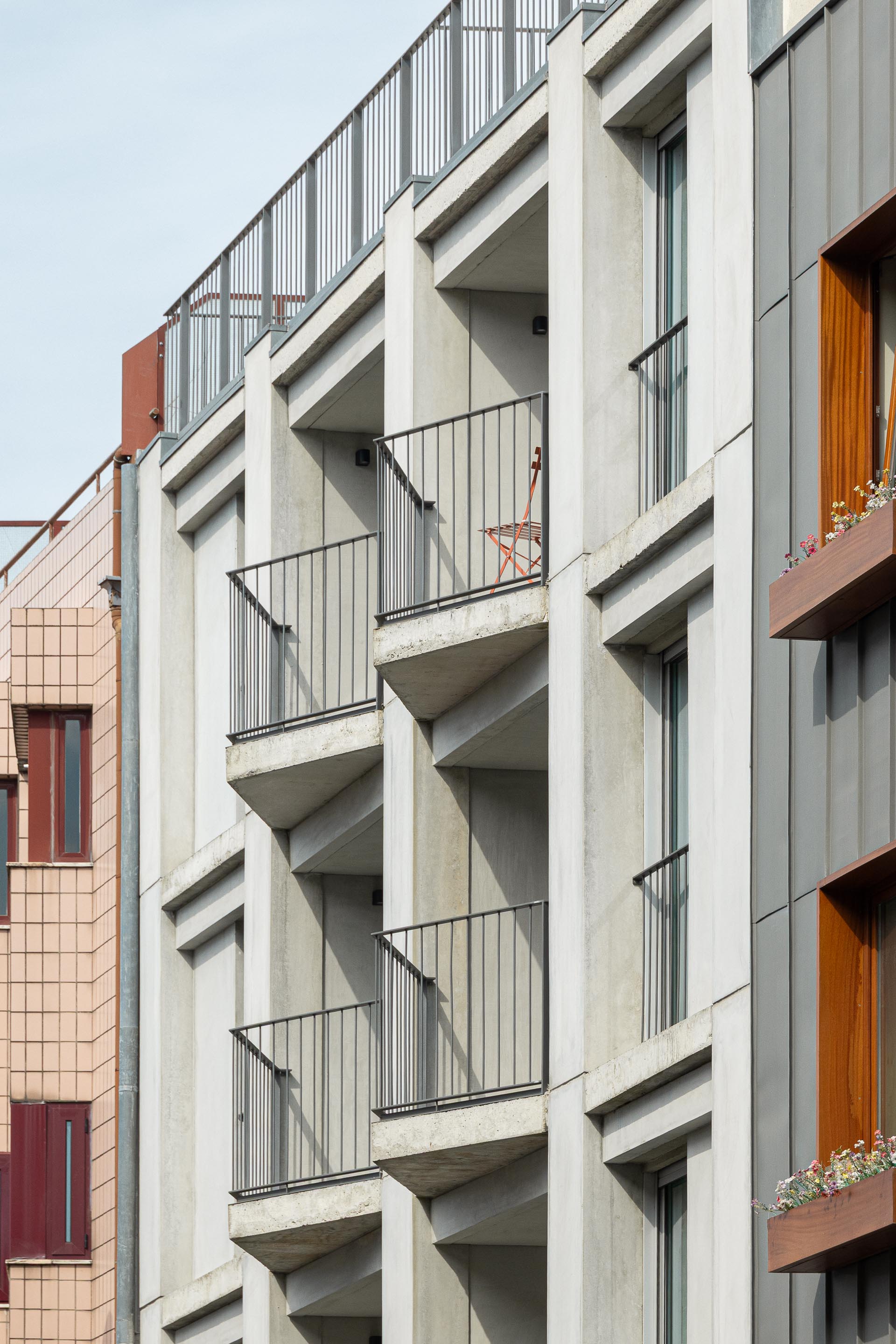 Detalhe da fachada com varandas em betão aparente e gradil metálico preto, emolduradas por painéis de betão pré-fabricado — Costa Cabral Building arquitectura ENTRETEMPOS + ATA Atelier fotografia Ivo Tavares