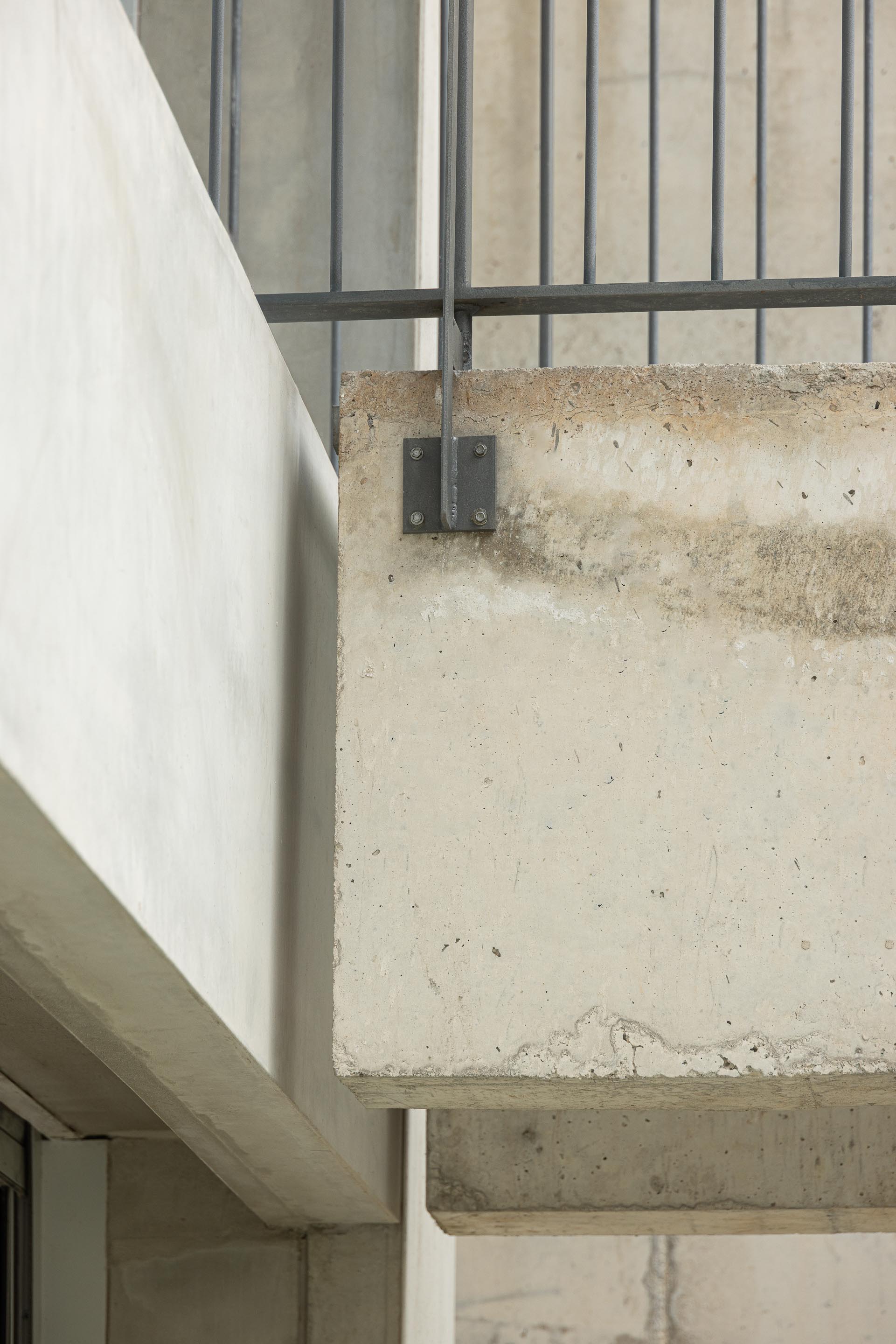 Detalhe construtivo da varanda em betão aparente, mostrando a textura do material e a fixação do gradil metálico — Costa Cabral Building arquitectura ENTRETEMPOS + ATA Atelier fotografia Ivo Tavares