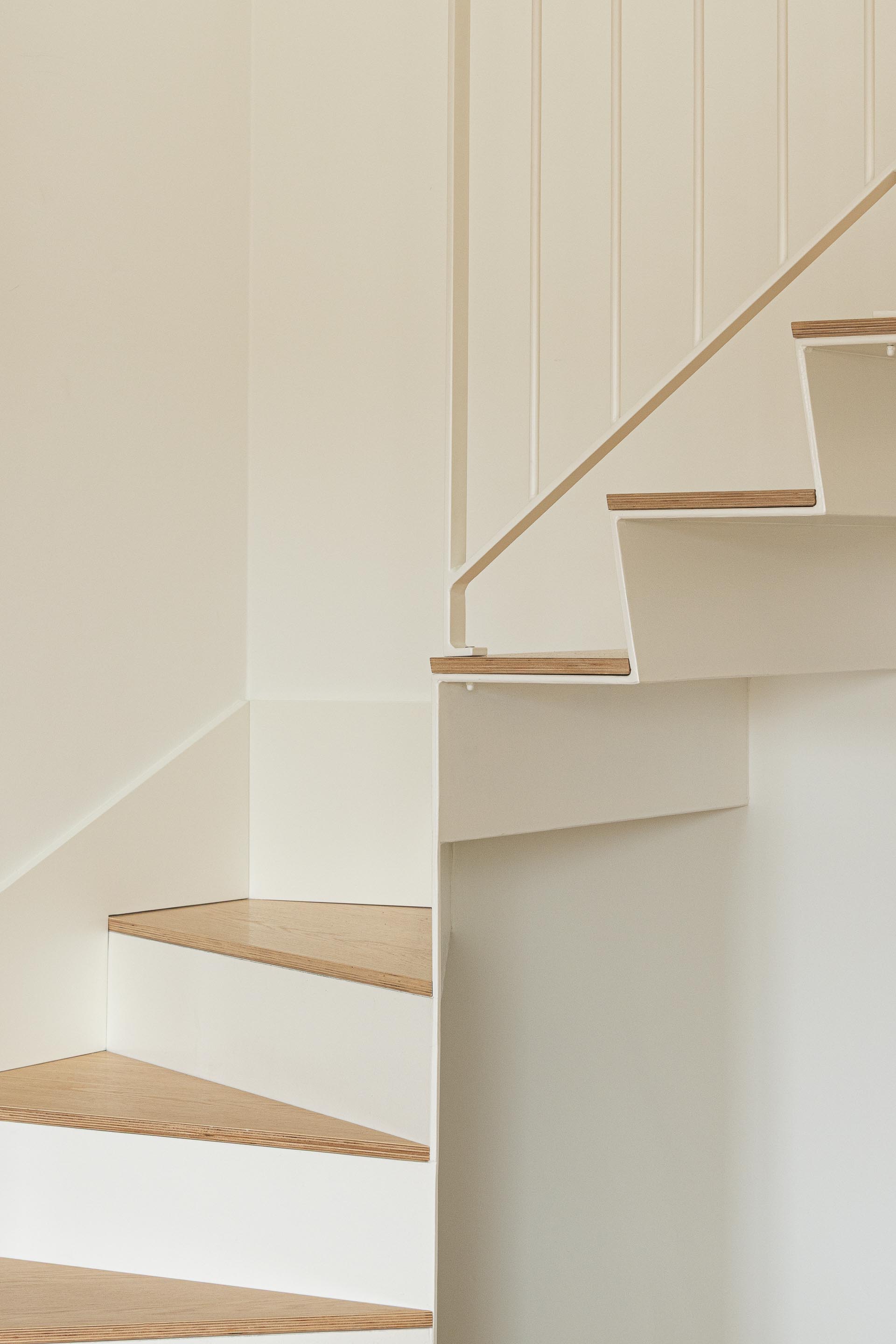 Detalhe da escada com degraus em madeira clara e estrutura metálica branca, criando um desenho leve e minimalista — Costa Cabral Building arquitectura ENTRETEMPOS + ATA Atelier fotografia Ivo Tavares