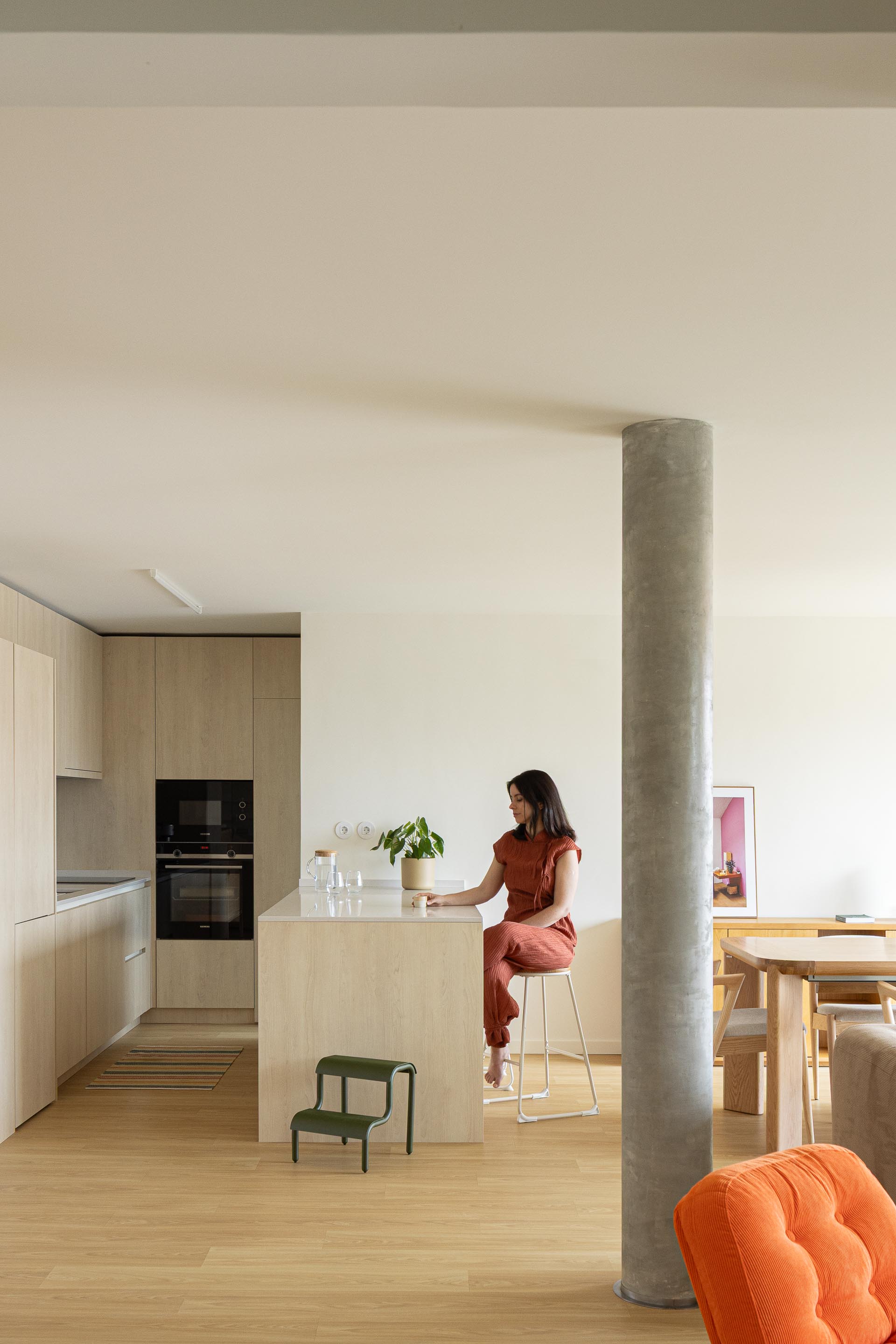 Cozinha e sala de jantar em plano aberto, com pilar cilíndrico de betão aparente e mobiliário em madeira clara — Costa Cabral Building arquitectura ENTRETEMPOS + ATA Atelier fotografia Ivo Tavares
