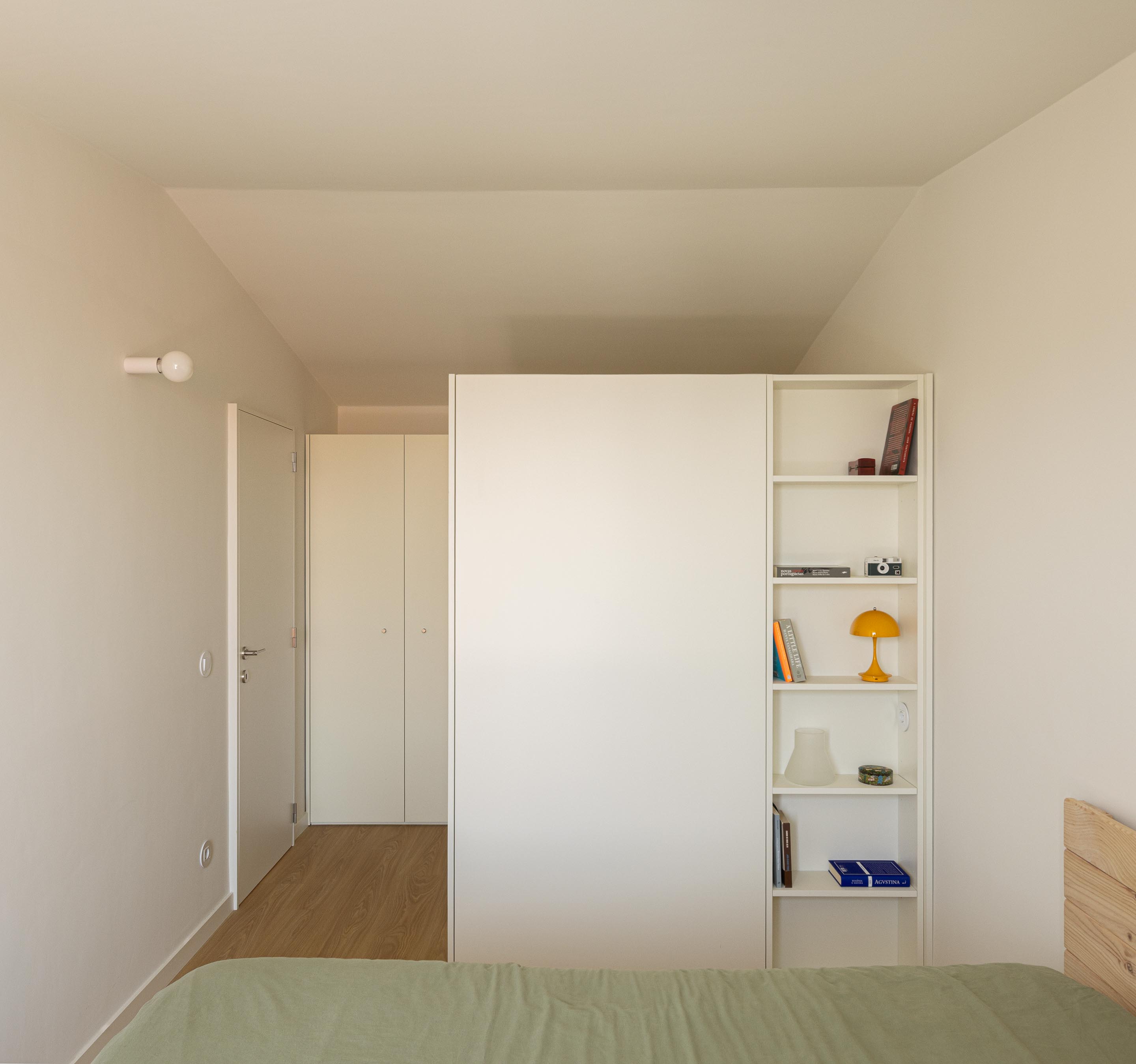 Quarto com pavimento em madeira clara, roupeiro branco com prateleiras integradas e cama em madeira — Costa Cabral Building arquitectura ENTRETEMPOS + ATA Atelier fotografia Ivo Tavares