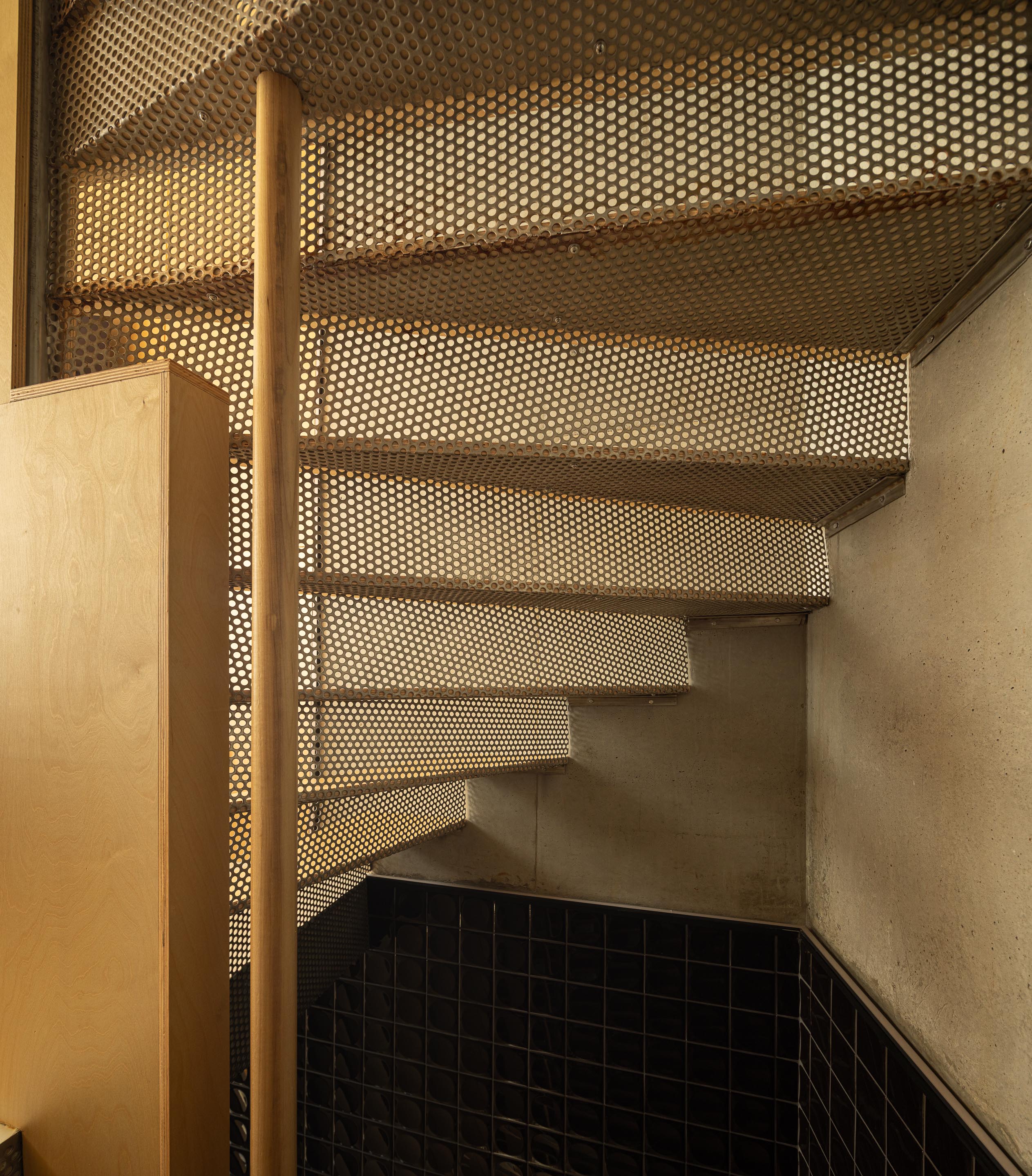 Escada em espiral com degraus em chapa metálica perfurada e madeira, iluminada por luz natural — MINI ATALHADA arquitectura SO Arquitetura & Design fotografia Ivo Tavares