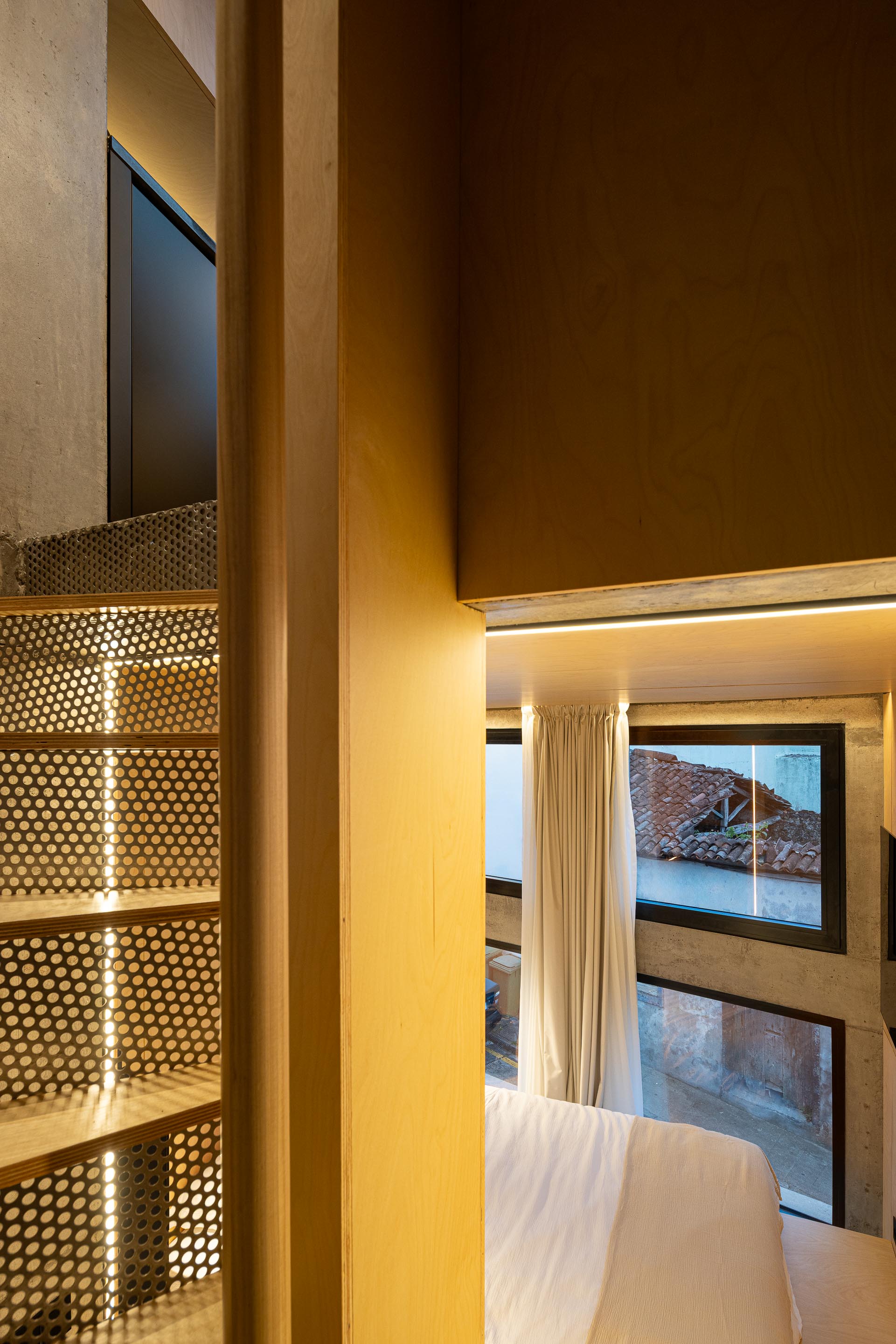 Quarto com paredes em madeira clara, vista para a escada e luz natural através de vãos — MINI ATALHADA arquitectura SO Arquitetura & Design fotografia Ivo Tavares
