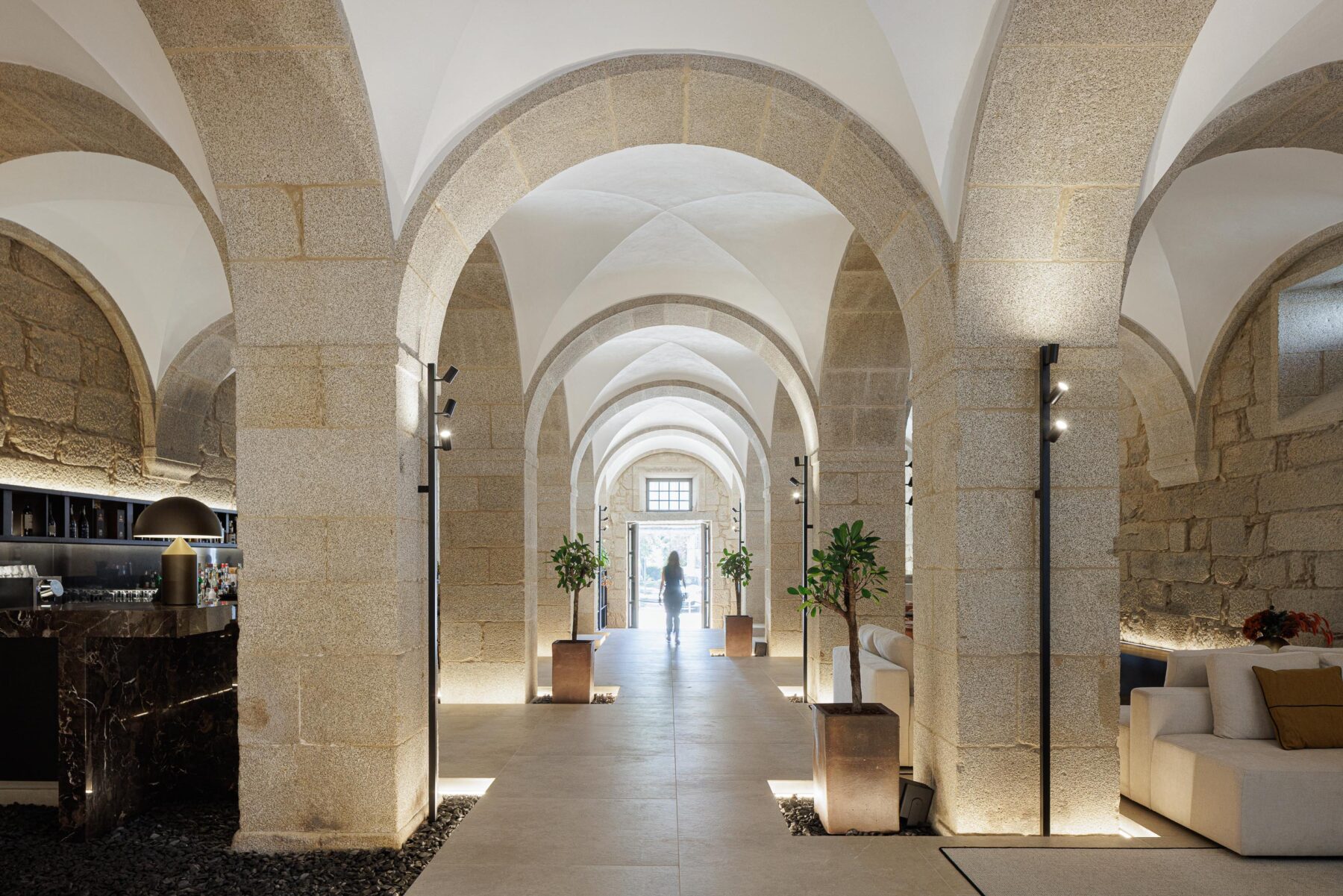 Hall de entrada com arcos de pedra e abóbadas brancas, pavimento em pedra e iluminação discreta, conduzindo ao exterior — MS COLLECTION AROUCA arquitectura MIMOOL ARQUITECTURA & INTERIORES fotografia Ivo Tavares