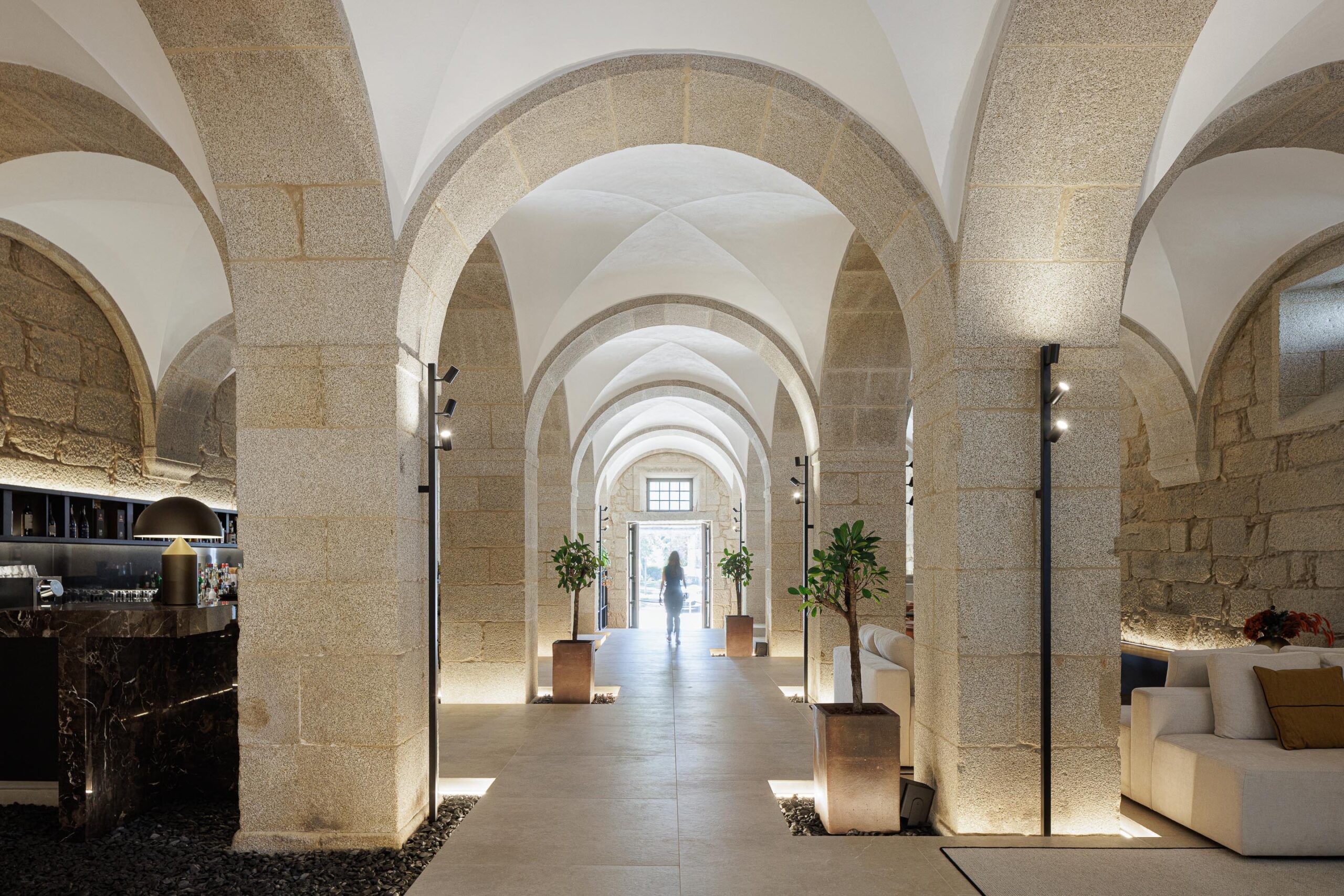 Hall de entrada com arcos de pedra e abóbadas brancas, pavimento em pedra e iluminação discreta, conduzindo ao exterior — MS COLLECTION AROUCA arquitectura MIMOOL ARQUITECTURA & INTERIORES fotografia Ivo Tavares