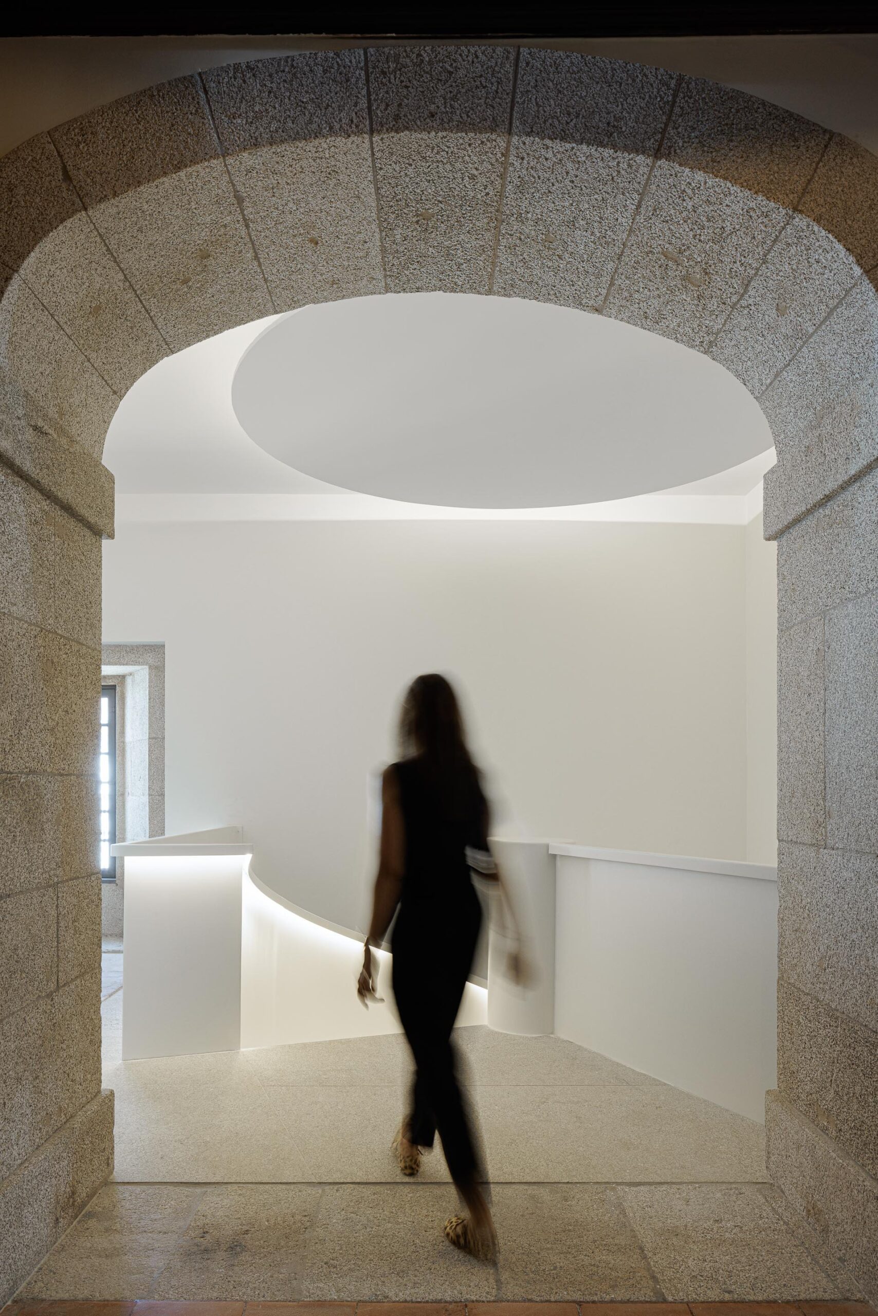 Escadaria em espiral branca com iluminação integrada, contrastando com a alvenaria de pedra existente — MS COLLECTION AROUCA arquitectura MIMOOL ARQUITECTURA & INTERIORES fotografia Ivo Tavares