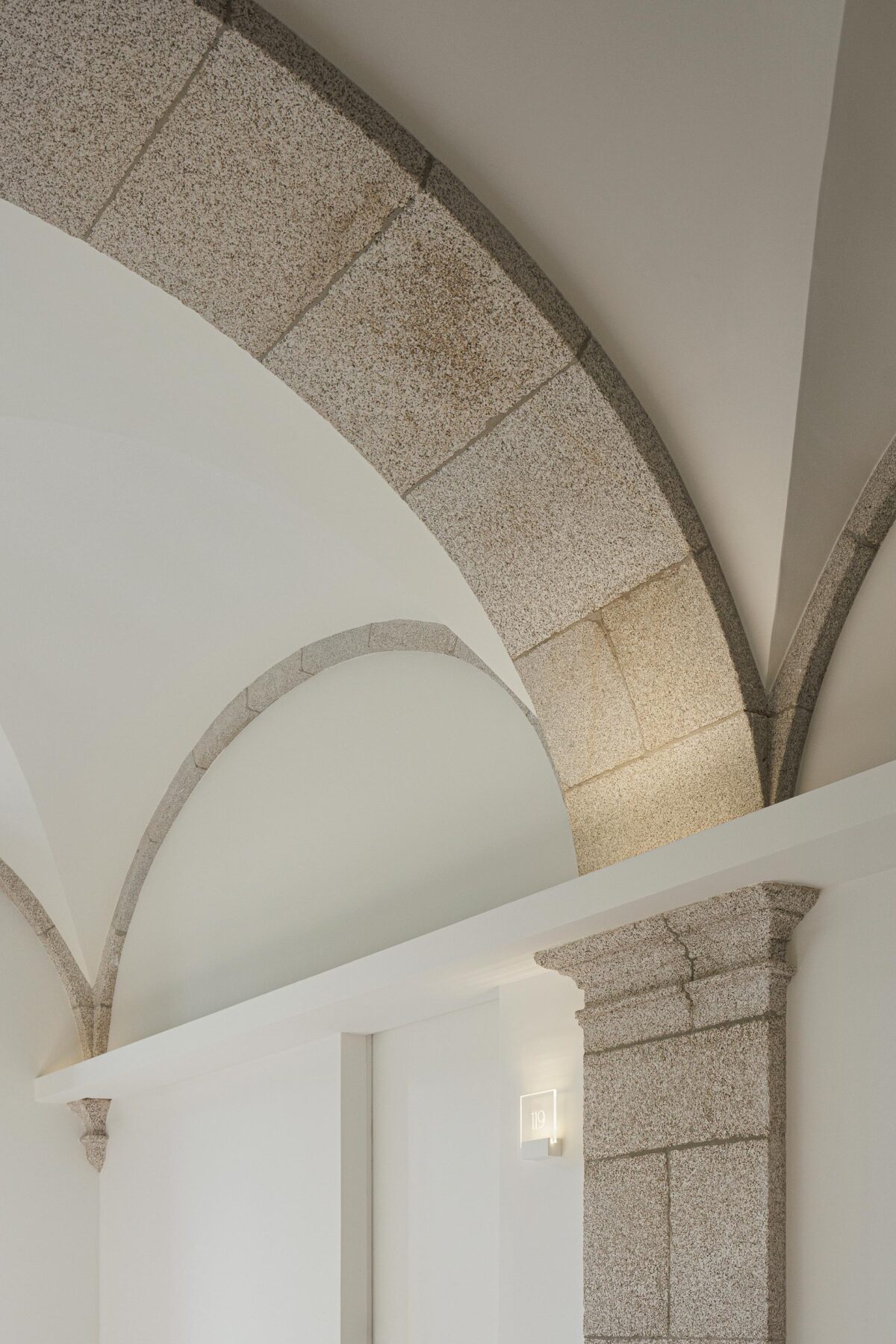 Detalhe de arco de pedra e abóbada branca, com iluminação embutida, realçando a textura da pedra — MS COLLECTION AROUCA arquitectura MIMOOL ARQUITECTURA & INTERIORES fotografia Ivo Tavares