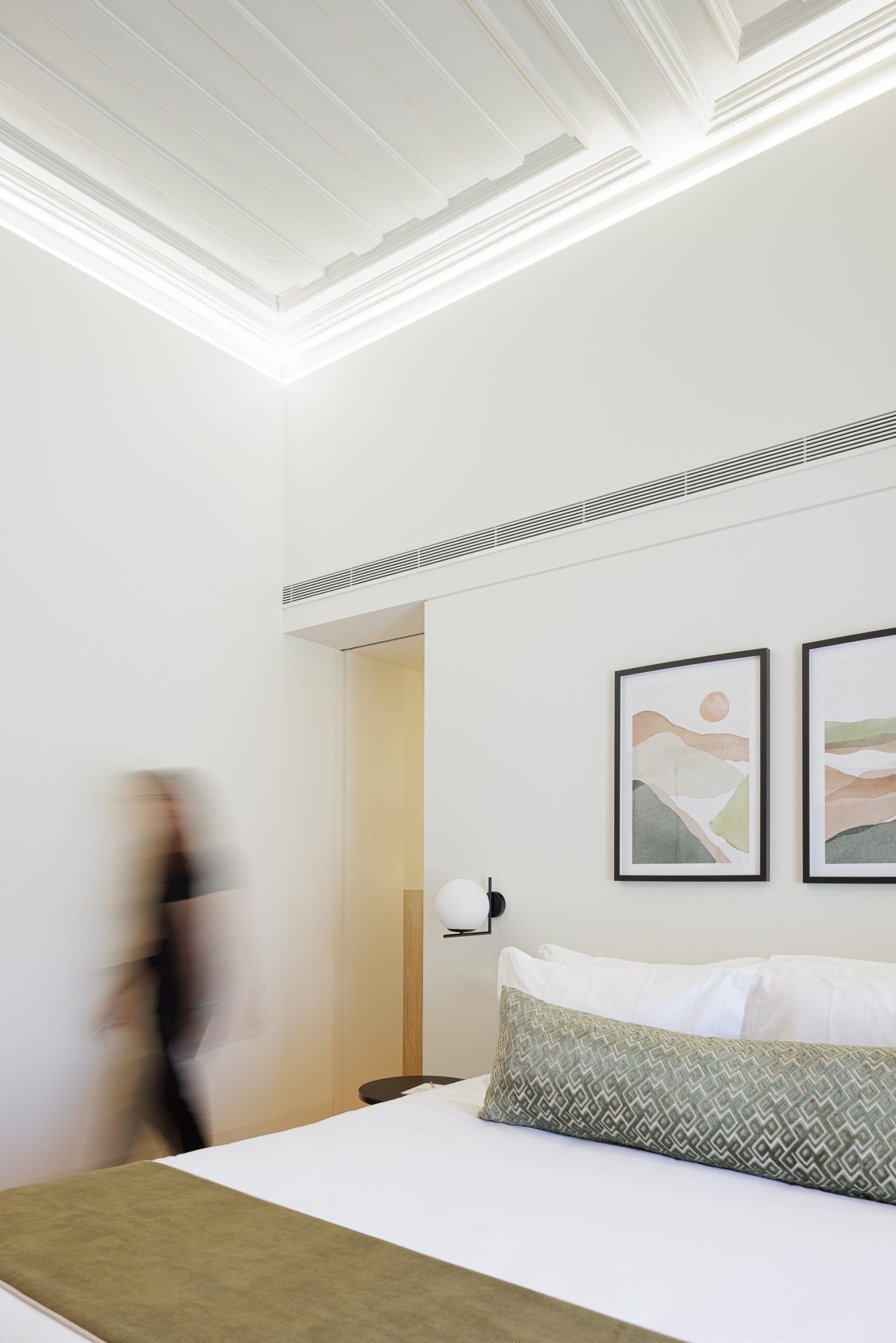 Quarto com cama, pavimento em madeira clara, teto branco trabalhado e iluminação indireta, com quadros na parede — MS COLLECTION AROUCA arquitectura MIMOOL ARQUITECTURA & INTERIORES fotografia Ivo Tavares
