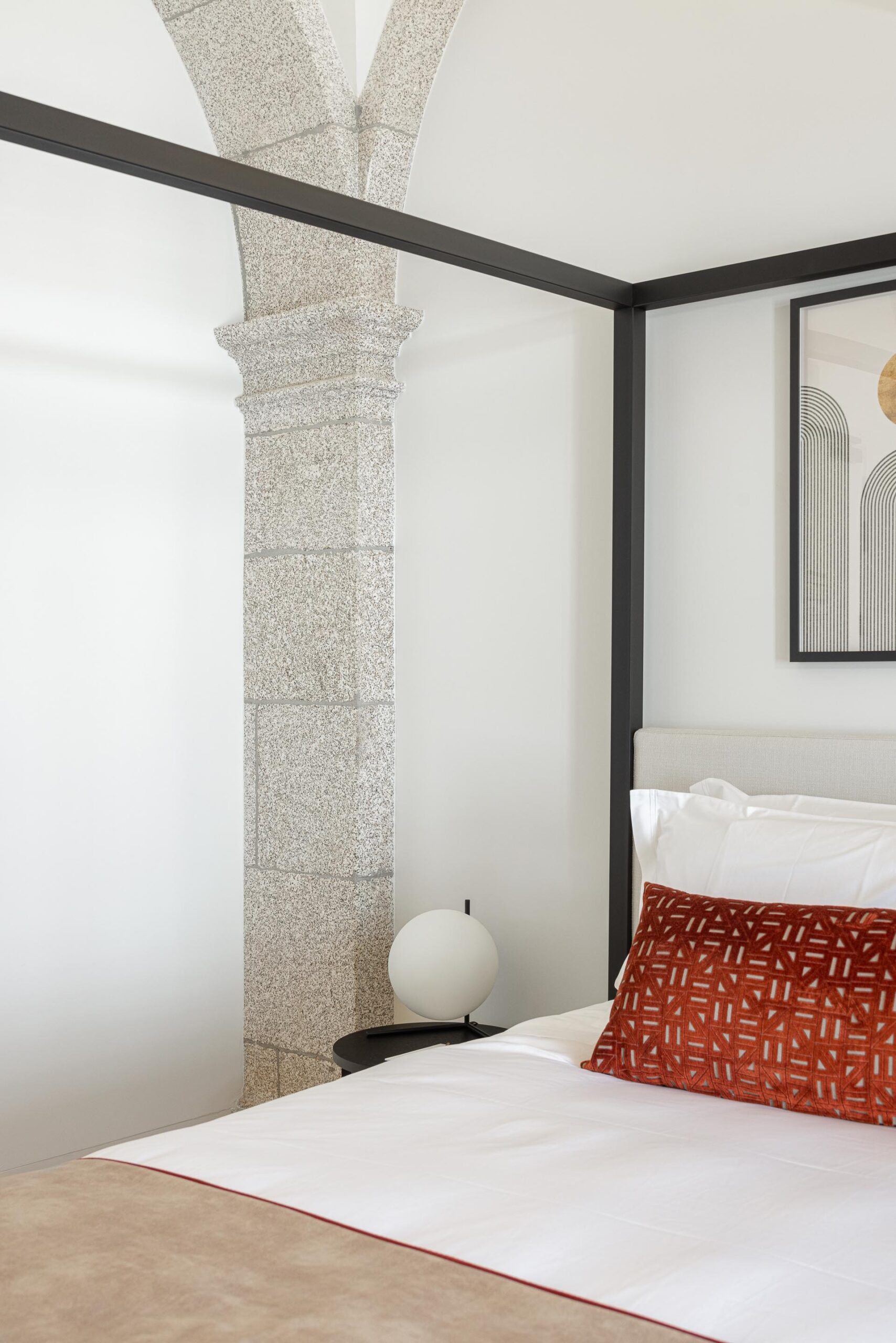 Detalhe do quarto com coluna de pedra e cama de dossel, candeeiro de mesa e almofada em tons quentes — MS COLLECTION AROUCA arquitectura MIMOOL ARQUITECTURA & INTERIORES fotografia Ivo Tavares