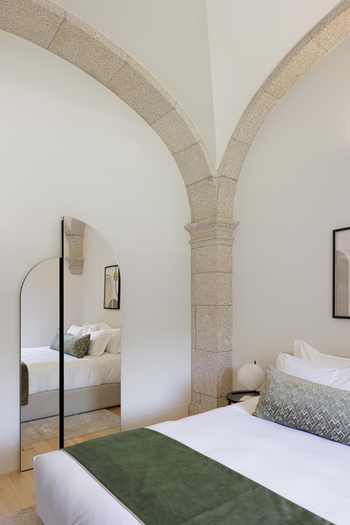 Detalhe do quarto com espelho em arco, coluna de pedra e abóbada, pavimento em madeira clara — MS COLLECTION AROUCA arquitectura MIMOOL ARQUITECTURA & INTERIORES fotografia Ivo Tavares