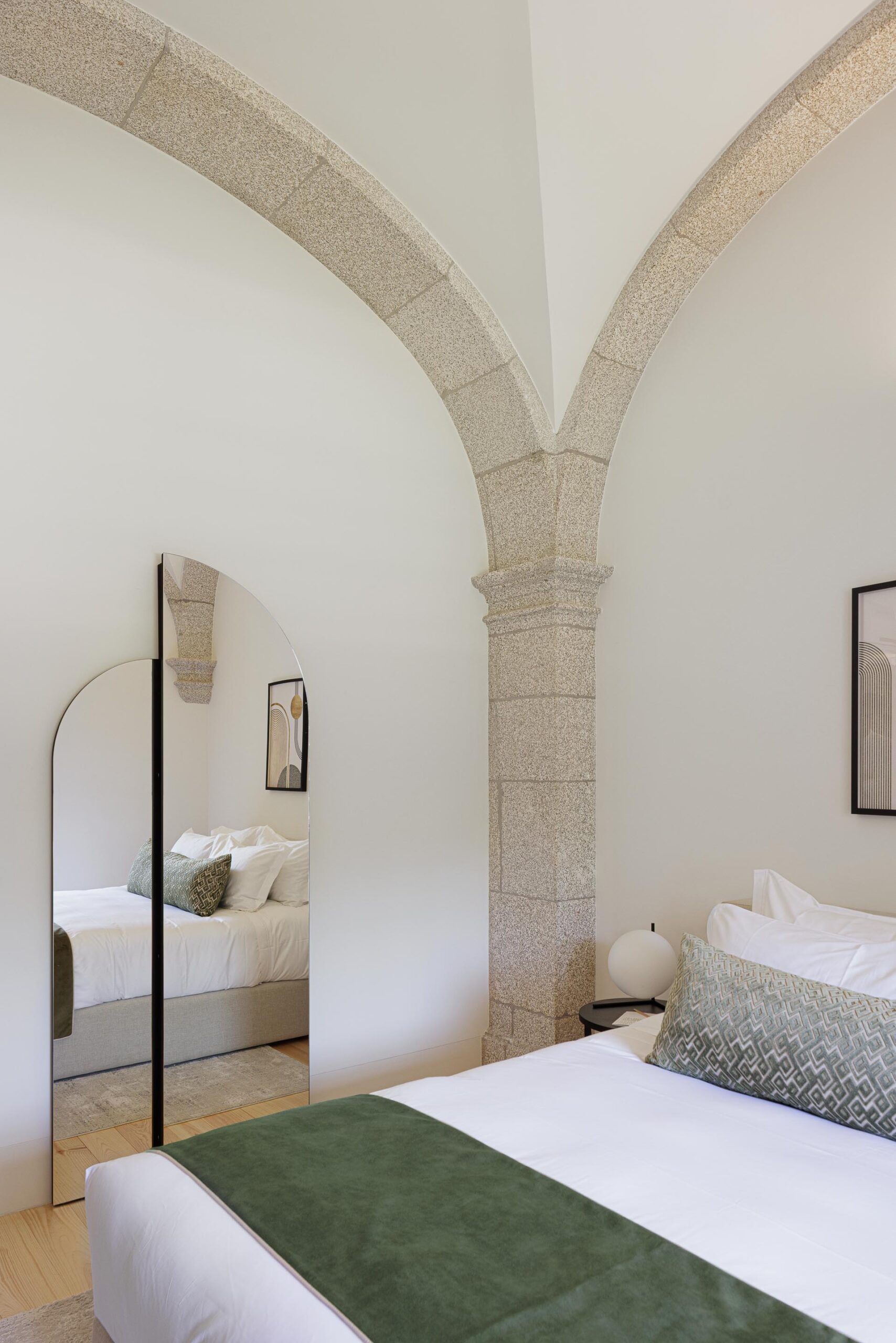 Detalhe do quarto com espelho em arco, coluna de pedra e abóbada, pavimento em madeira clara — MS COLLECTION AROUCA arquitectura MIMOOL ARQUITECTURA & INTERIORES fotografia Ivo Tavares