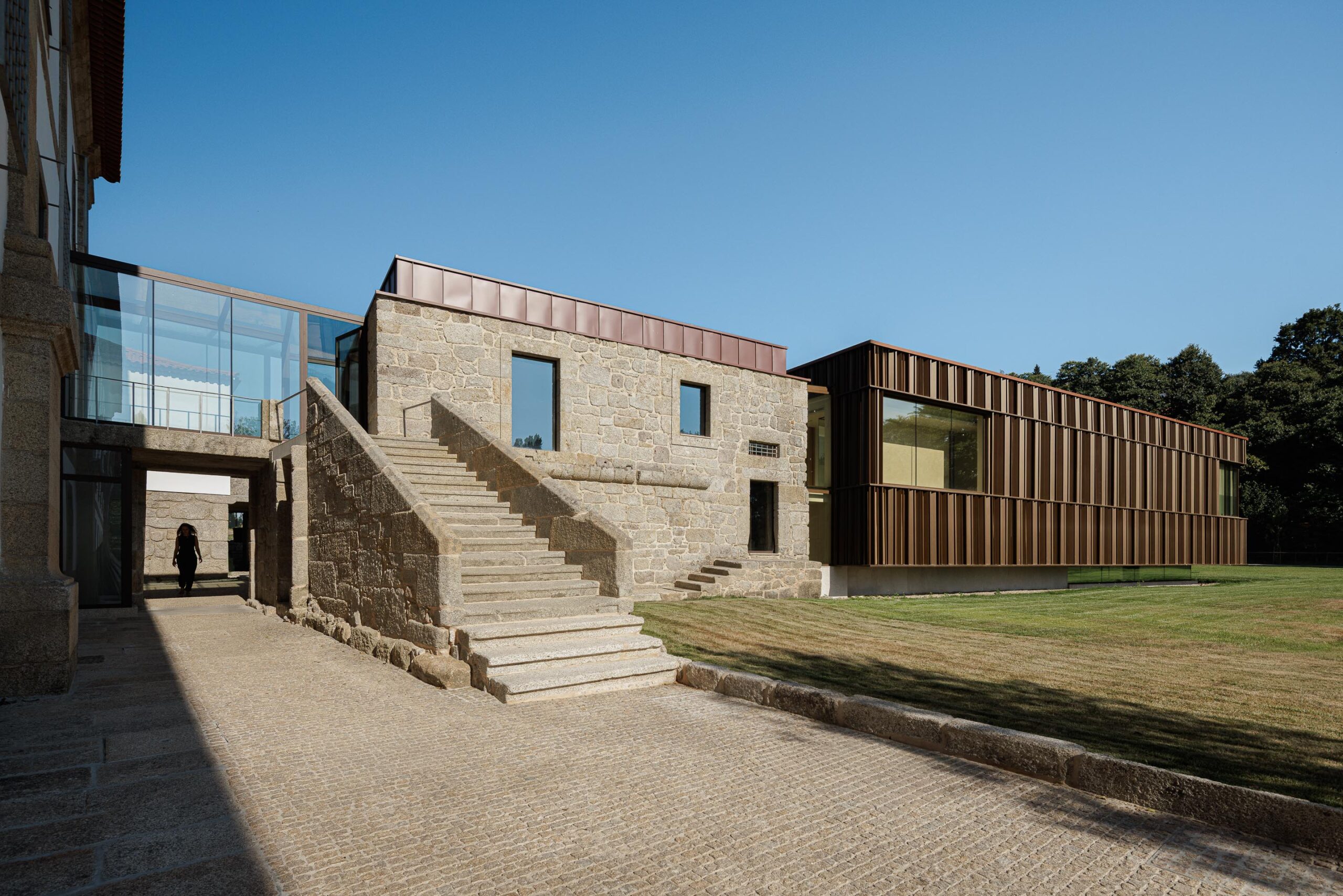 Escadaria exterior em pedra, ligando o edifício histórico ao novo volume em lamelas metálicas e vidro — MS COLLECTION AROUCA arquitectura MIMOOL ARQUITECTURA & INTERIORES fotografia Ivo Tavares